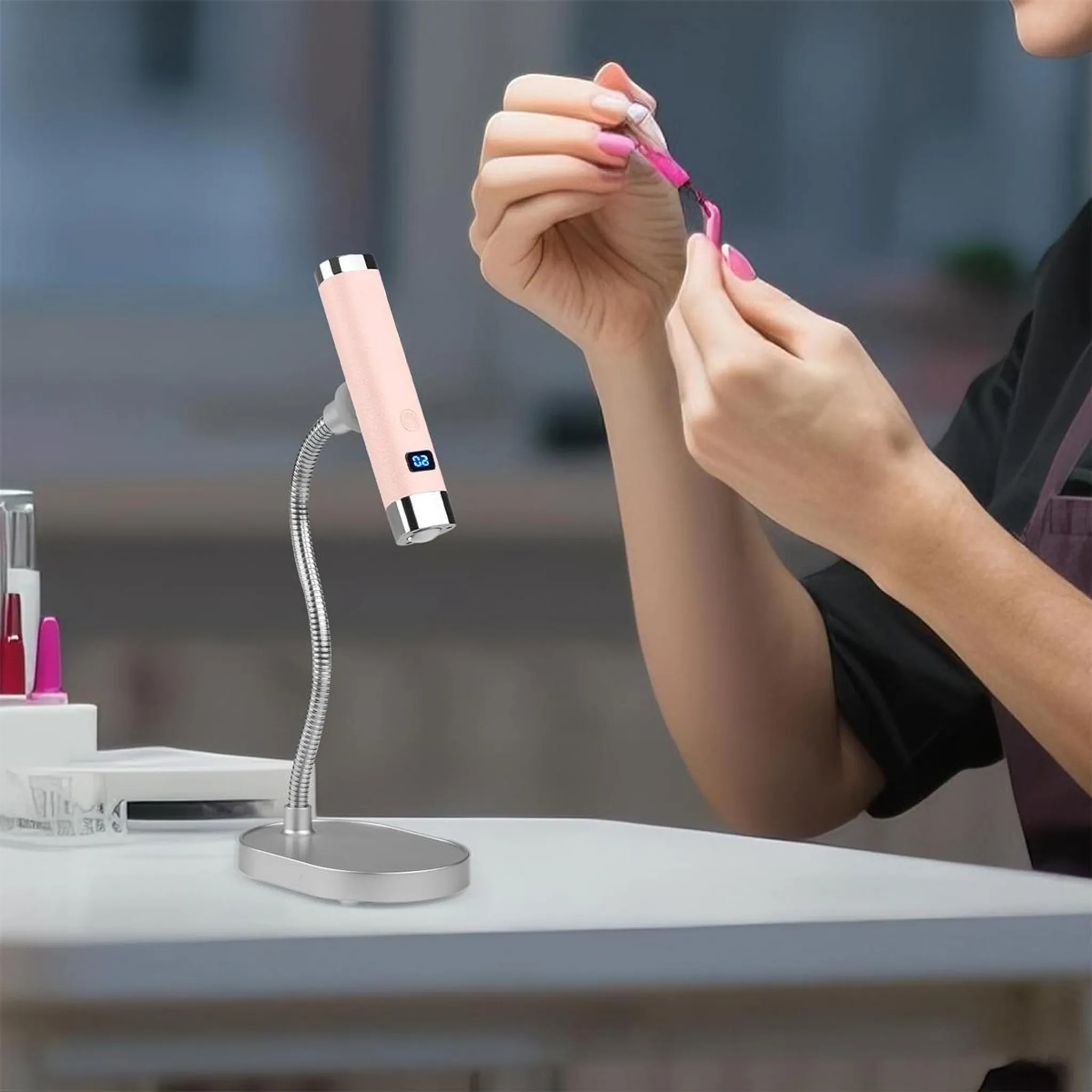 Eine Person trägt mit einem Pinsel rosa Nagellack auf ihren Fingernagel auf.