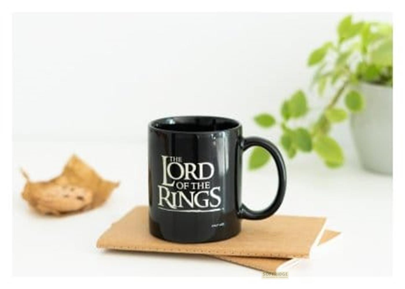 Schwarze Tasse mit „Der Herr der Ringe“-Logo auf Notizbüchern, daneben ein Blatt.