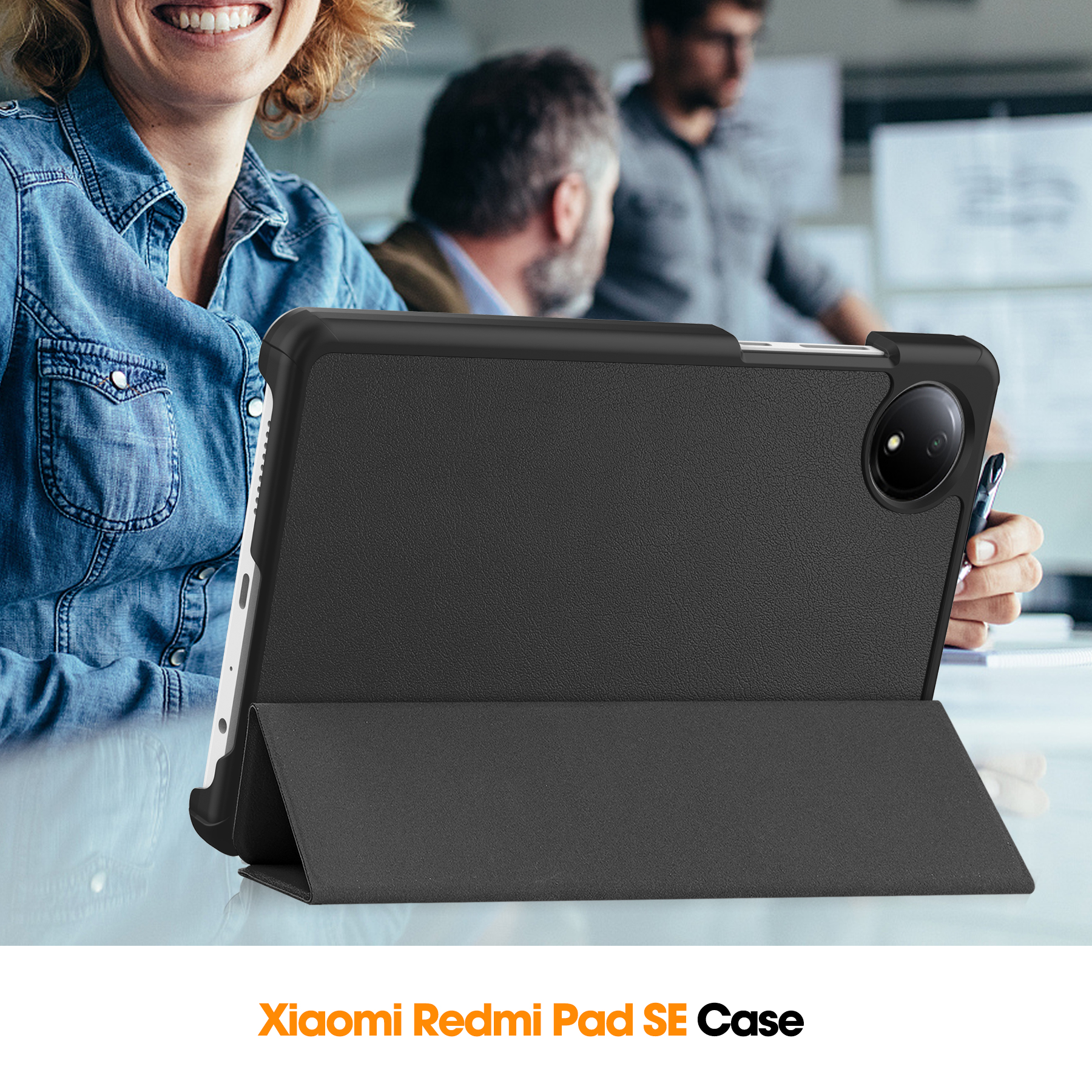 Schwarze Xiaomi Redmi Pad SE Hülle auf einem Tisch mit verschwommenen Personen im Hintergrund.