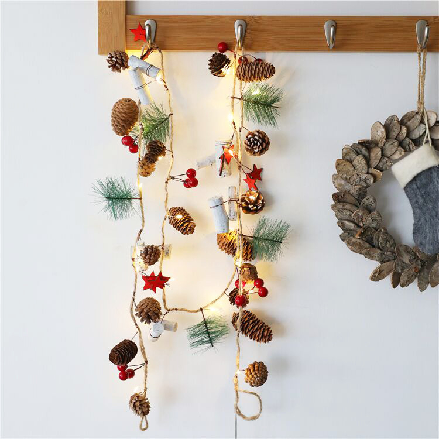 Weihnachtsdeko mit Tannenzapfen, Beeren, Sternen und Lichterkette an Haken.