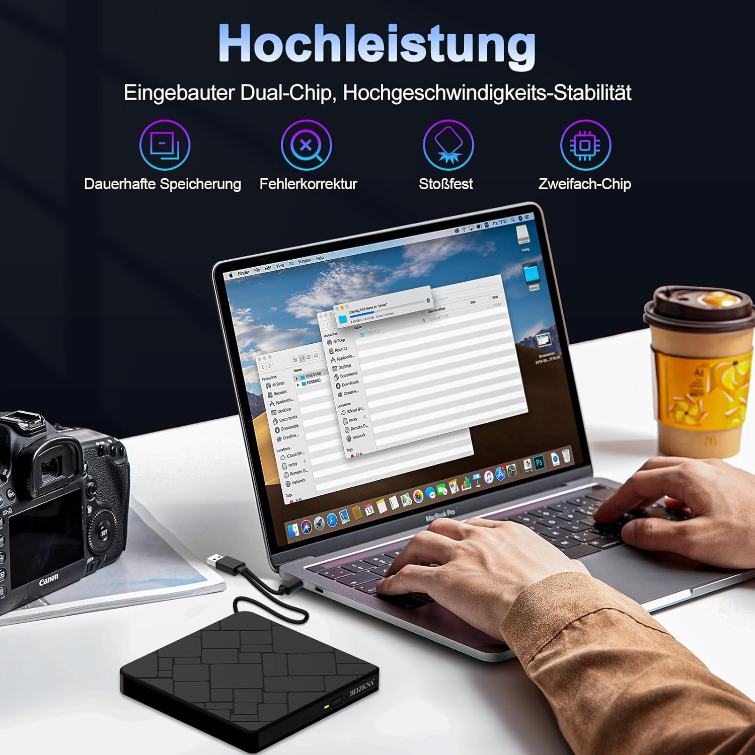 Laptop mit externer Festplatte, Kamera und Kaffeebecher. Text auf Deutsch.