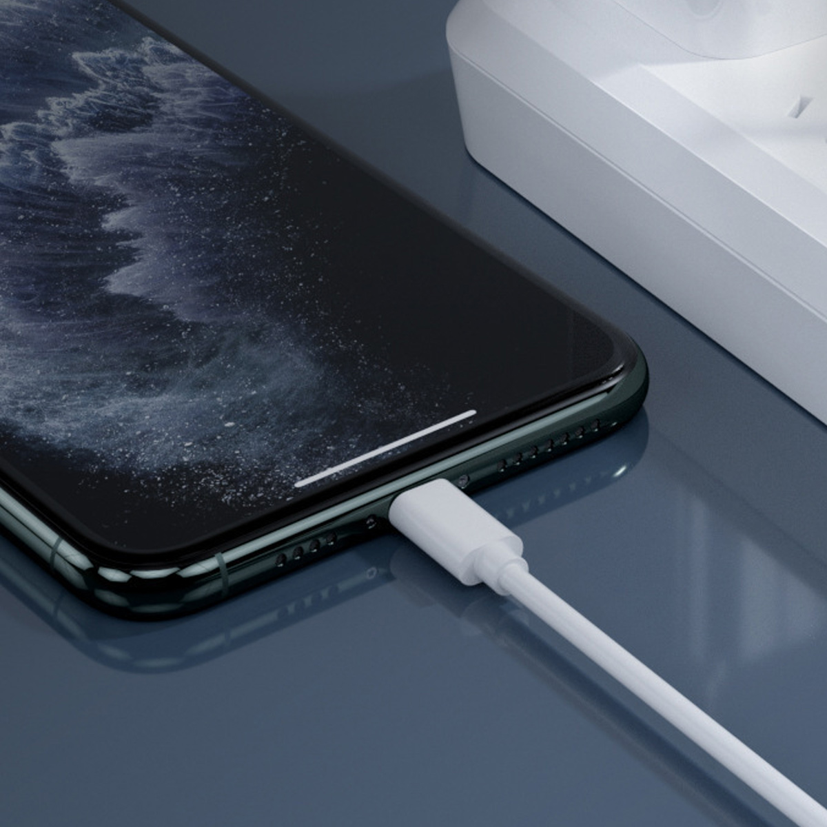 Ein weißes Ladekabel wird in ein dunkles Smartphone gesteckt.