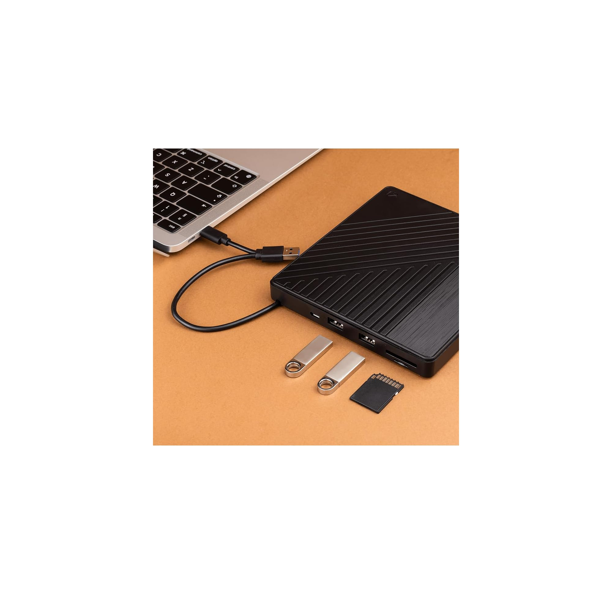 Ein Laptop ist mit einem schwarzen Festplattengehäuse verbunden, daneben liegen USB-Sticks und eine SD-Karte.