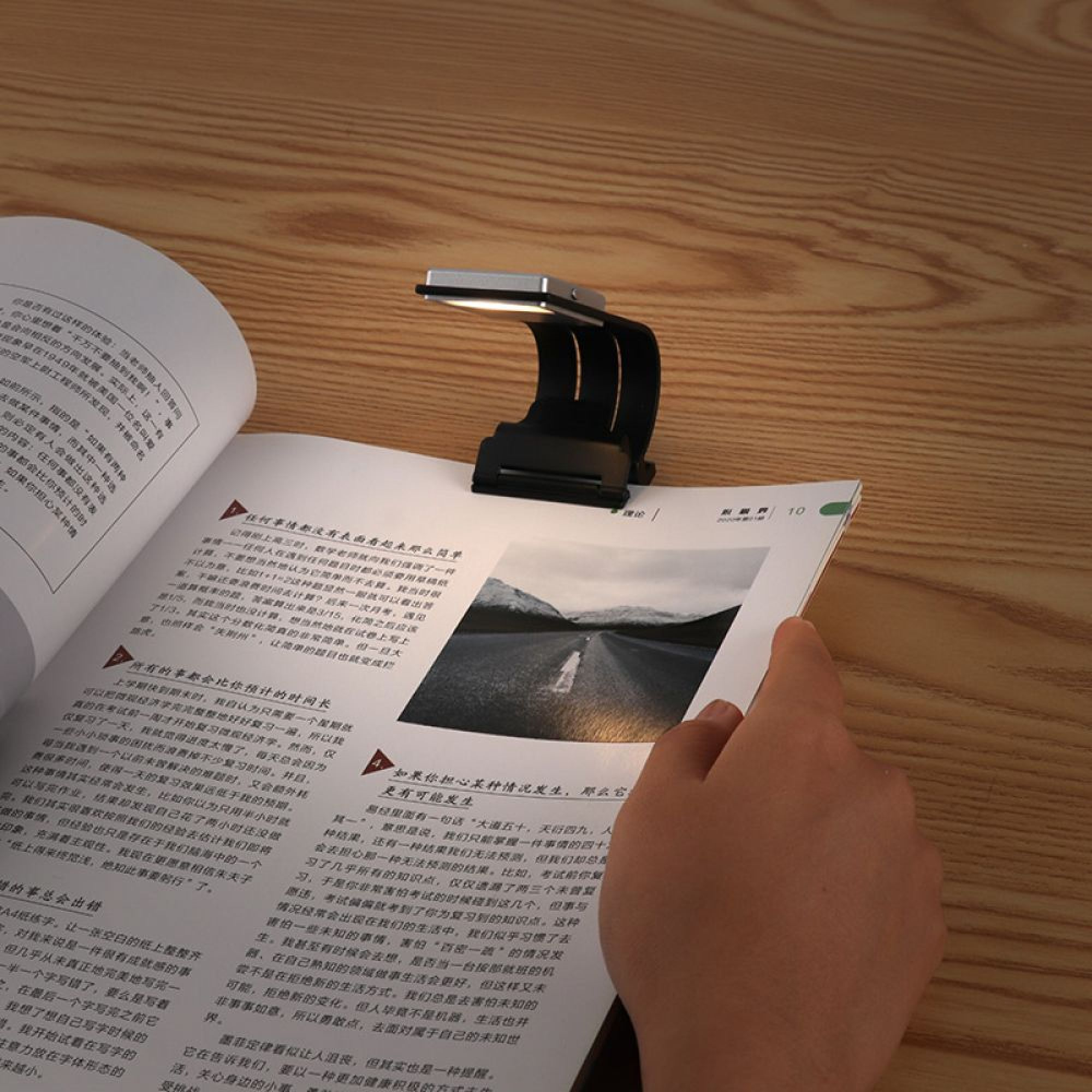 Ein Buch mit einem Buchlicht, das auf eine Seite scheint. Holztisch im Hintergrund.