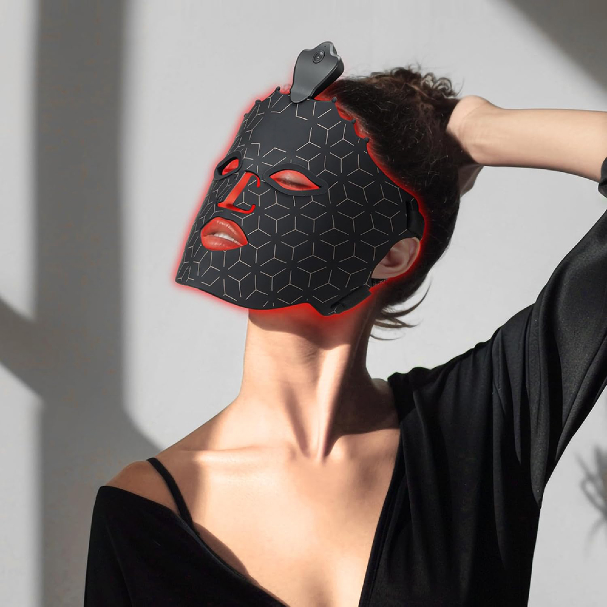 Eine Frau trägt eine schwarze LED-Gesichtsmaske mit roten Lichtern und rotem Mund.