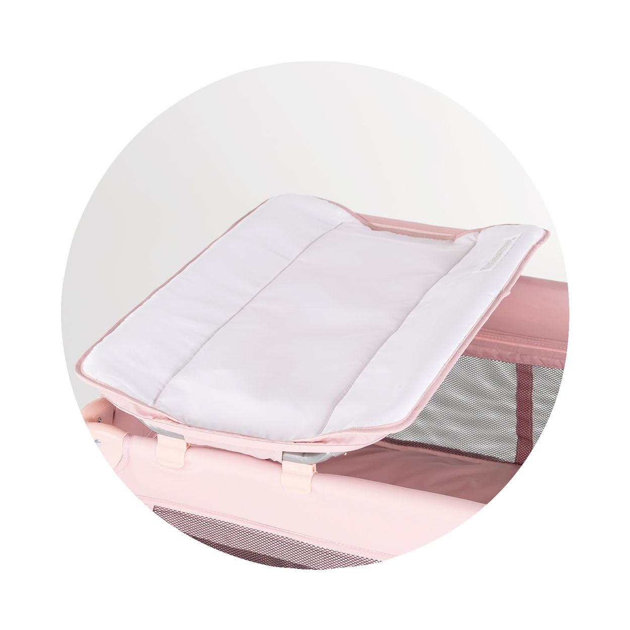 Ein rosa Reisebett mit einer weißen, gepolsterten Liegefläche.