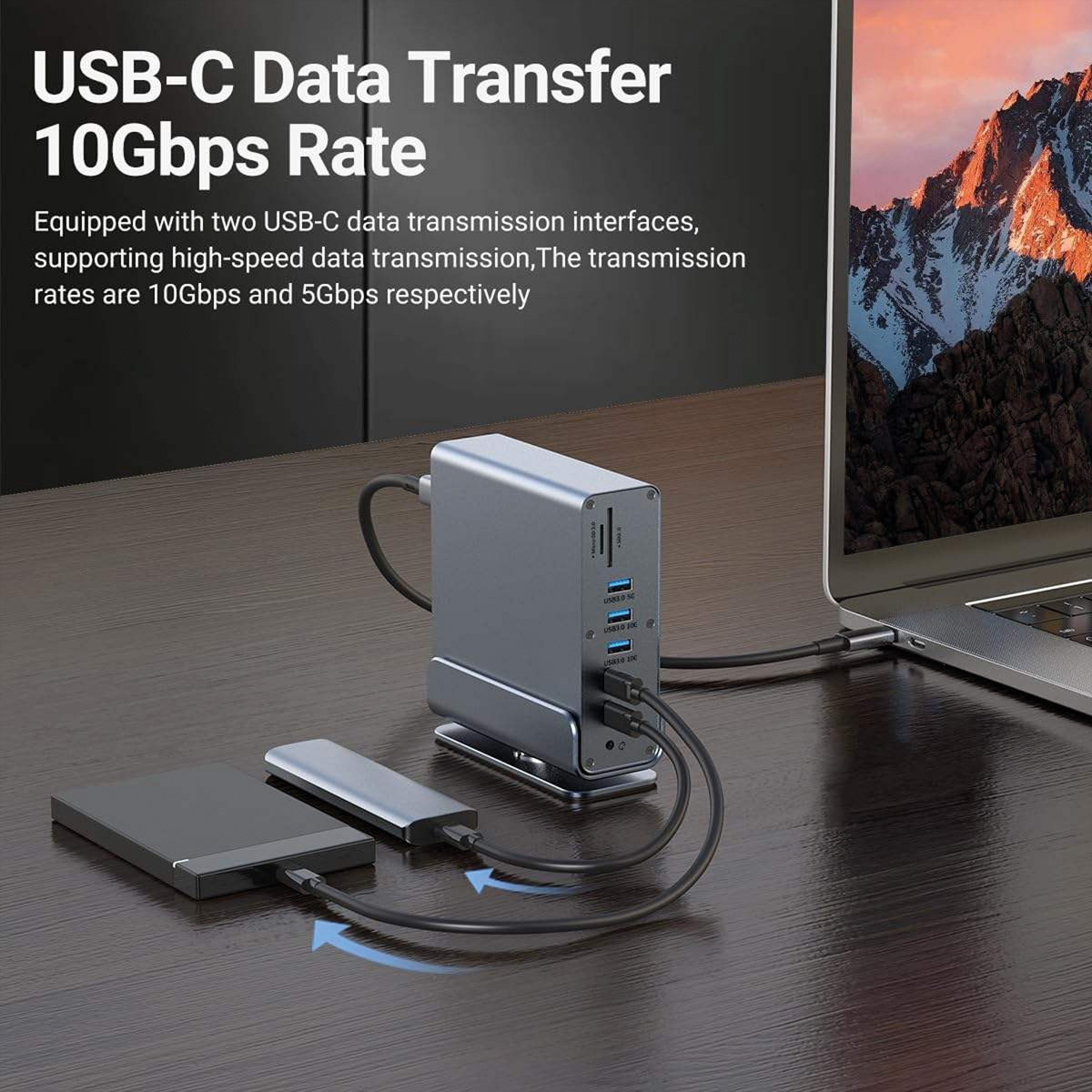 Grauer USB-C-Hub mit externer Festplatte und Laptop auf einem Holztisch.