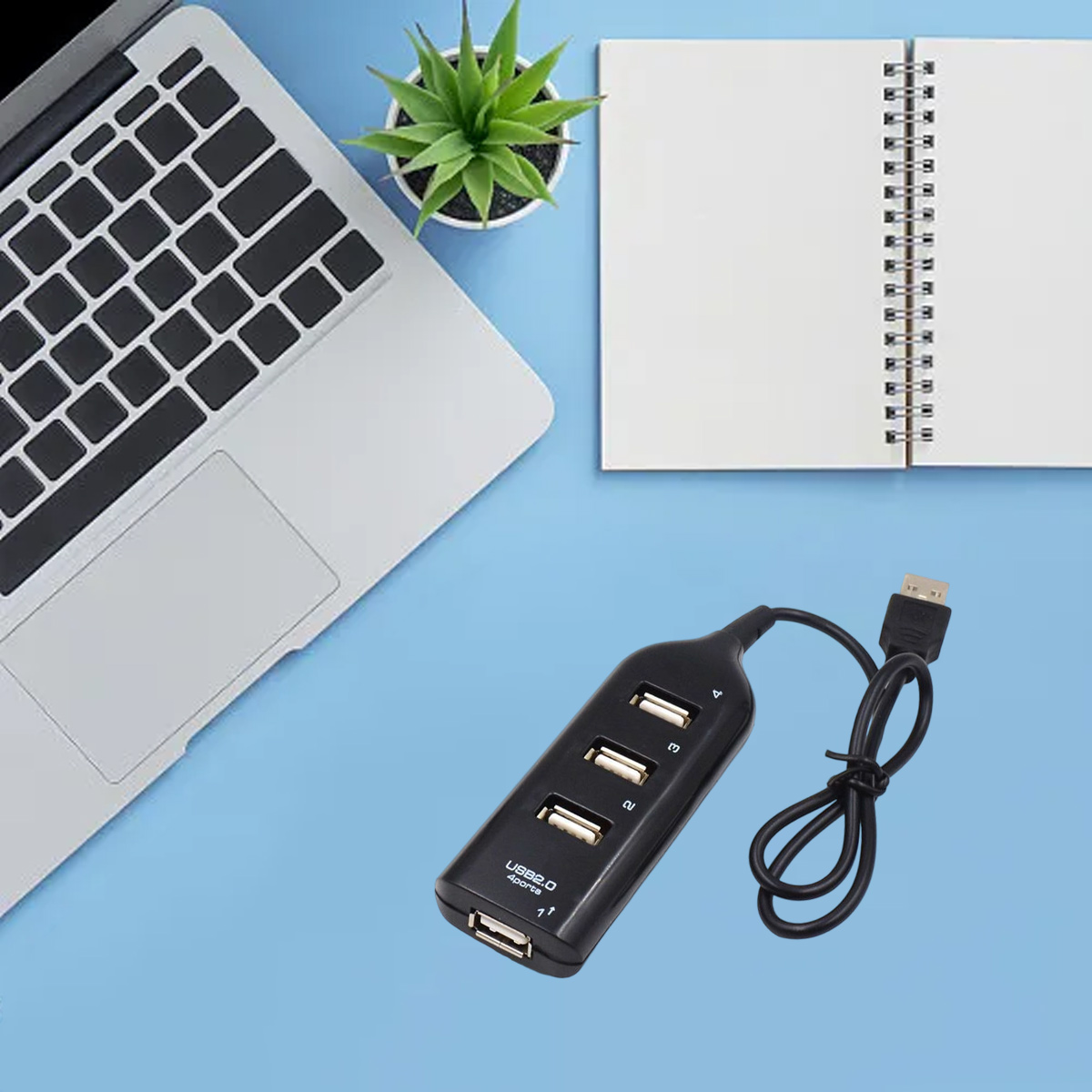 Ein schwarzer USB-Hub mit 4 Anschlüssen liegt neben einem Laptop und einem Notizbuch.