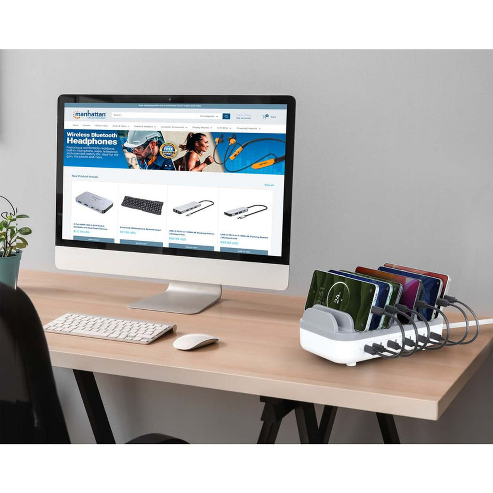 Ein Schreibtisch mit einem Monitor, Tastatur und Maus, daneben ein Ladegerät mit fünf Smartphones.