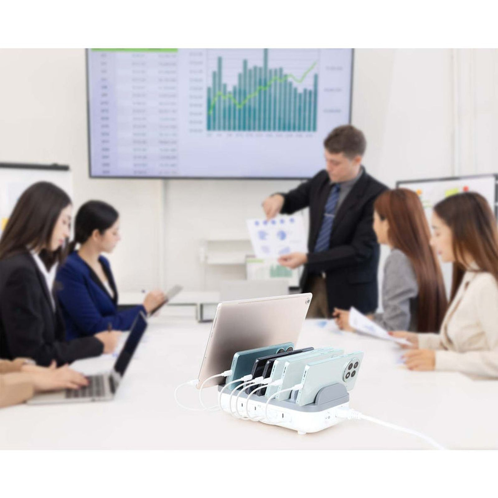 Männer und Frauen in einem Besprechungsraum mit einem Monitor, der ein Diagramm zeigt.