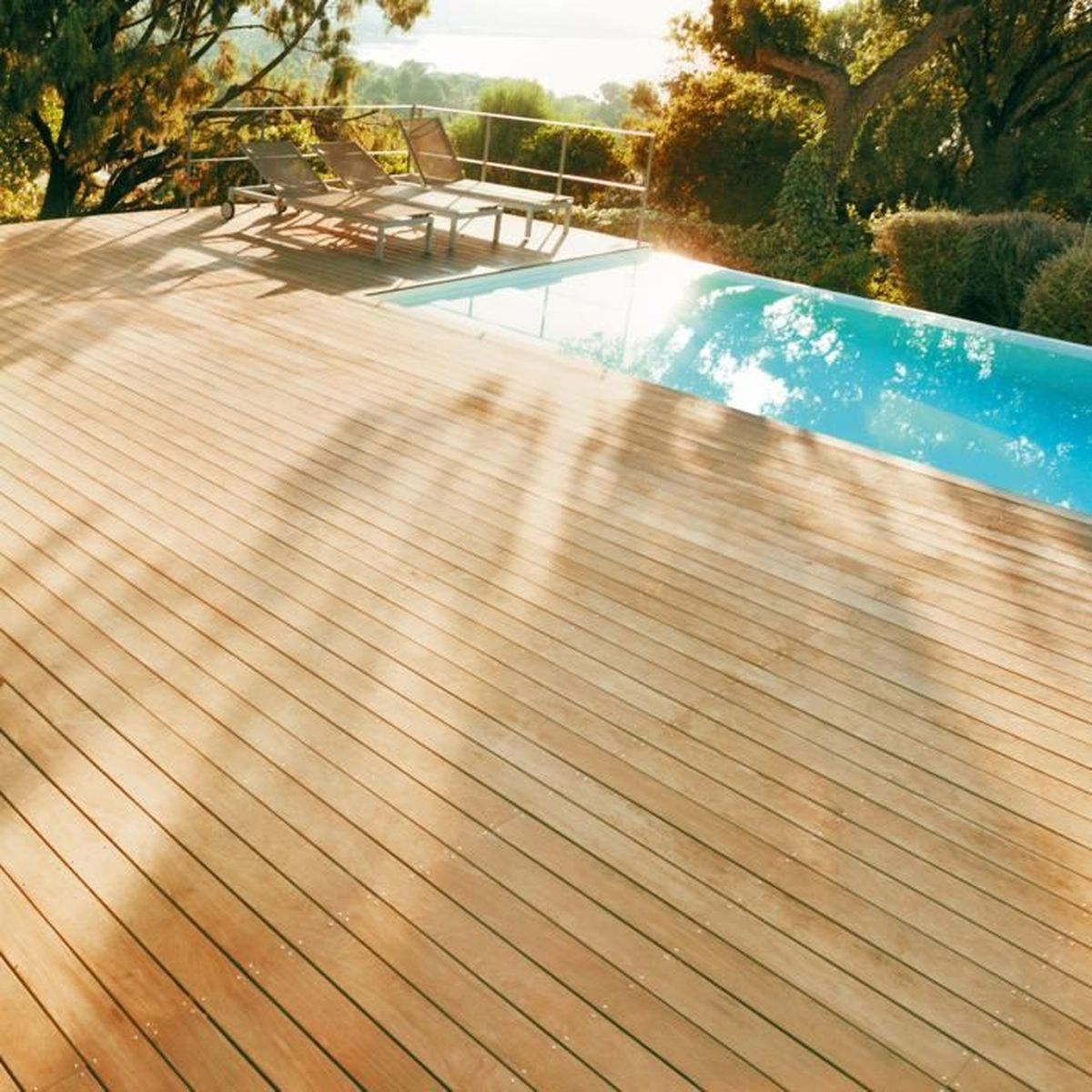 Holzdeck mit Pool und Liegestühlen im Freien.