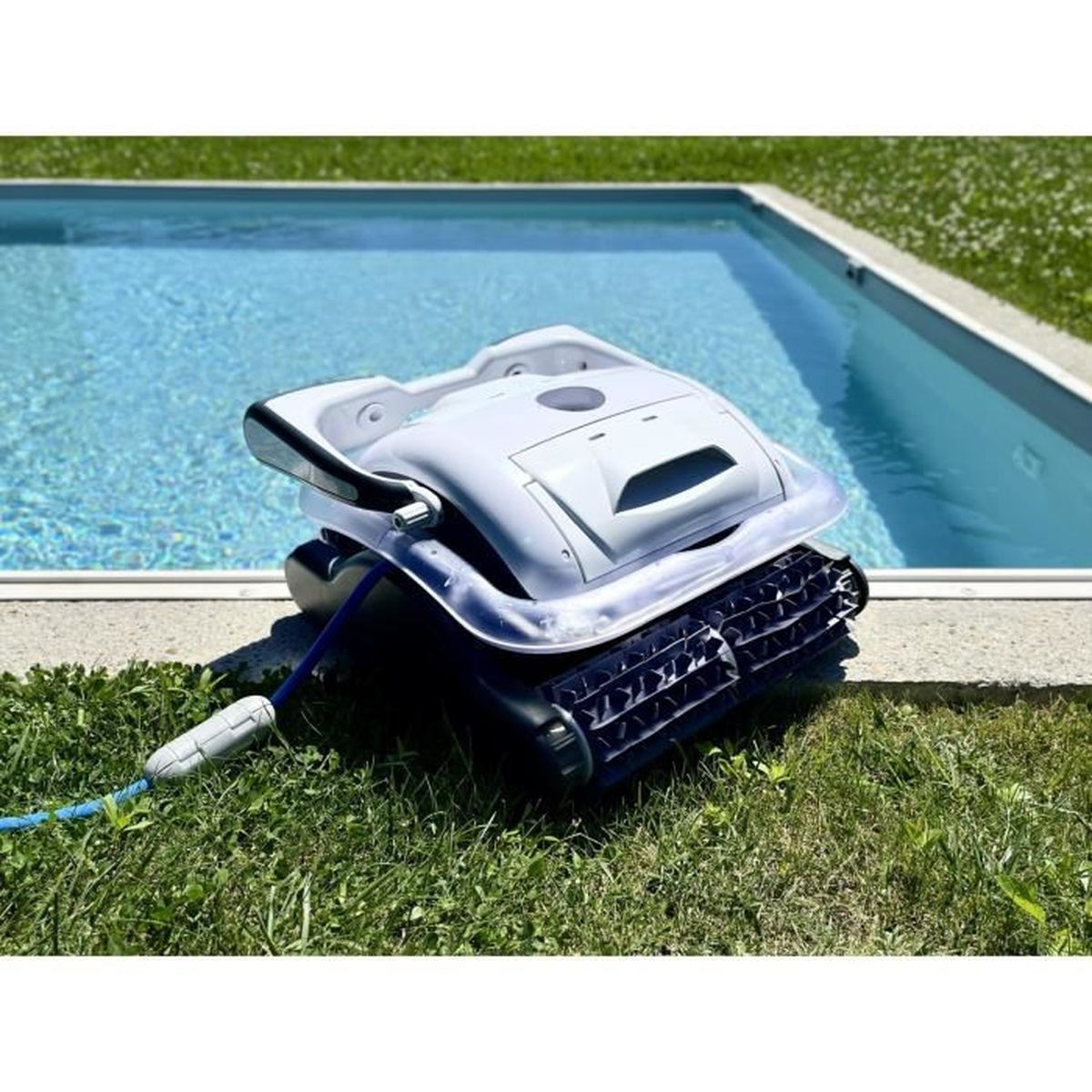 Ein weißer Poolroboter mit blauem Schlauch liegt auf dem Rasen neben dem Pool.