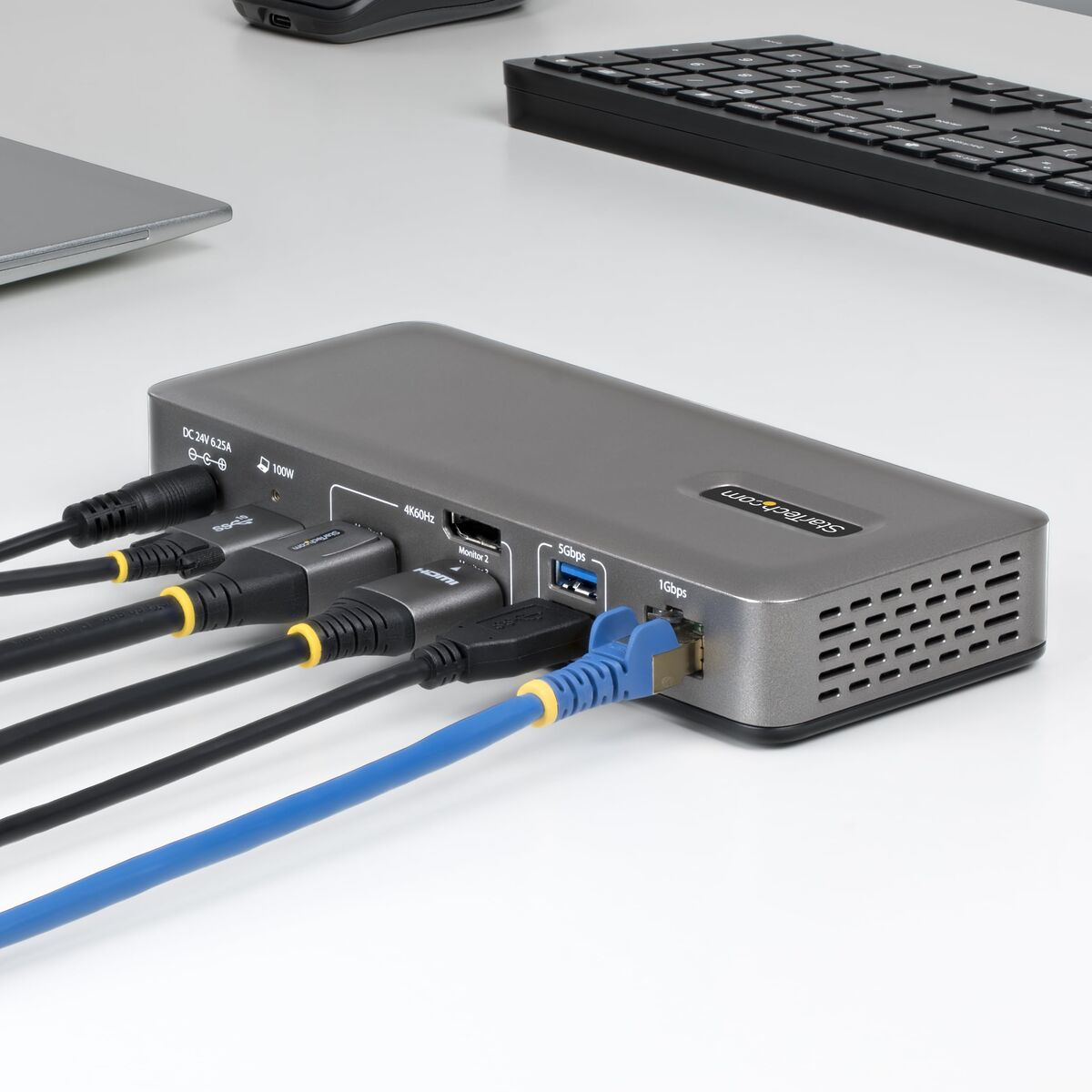 Graue Dockingstation mit angeschlossenen Kabeln: HDMI, USB, Ethernet.