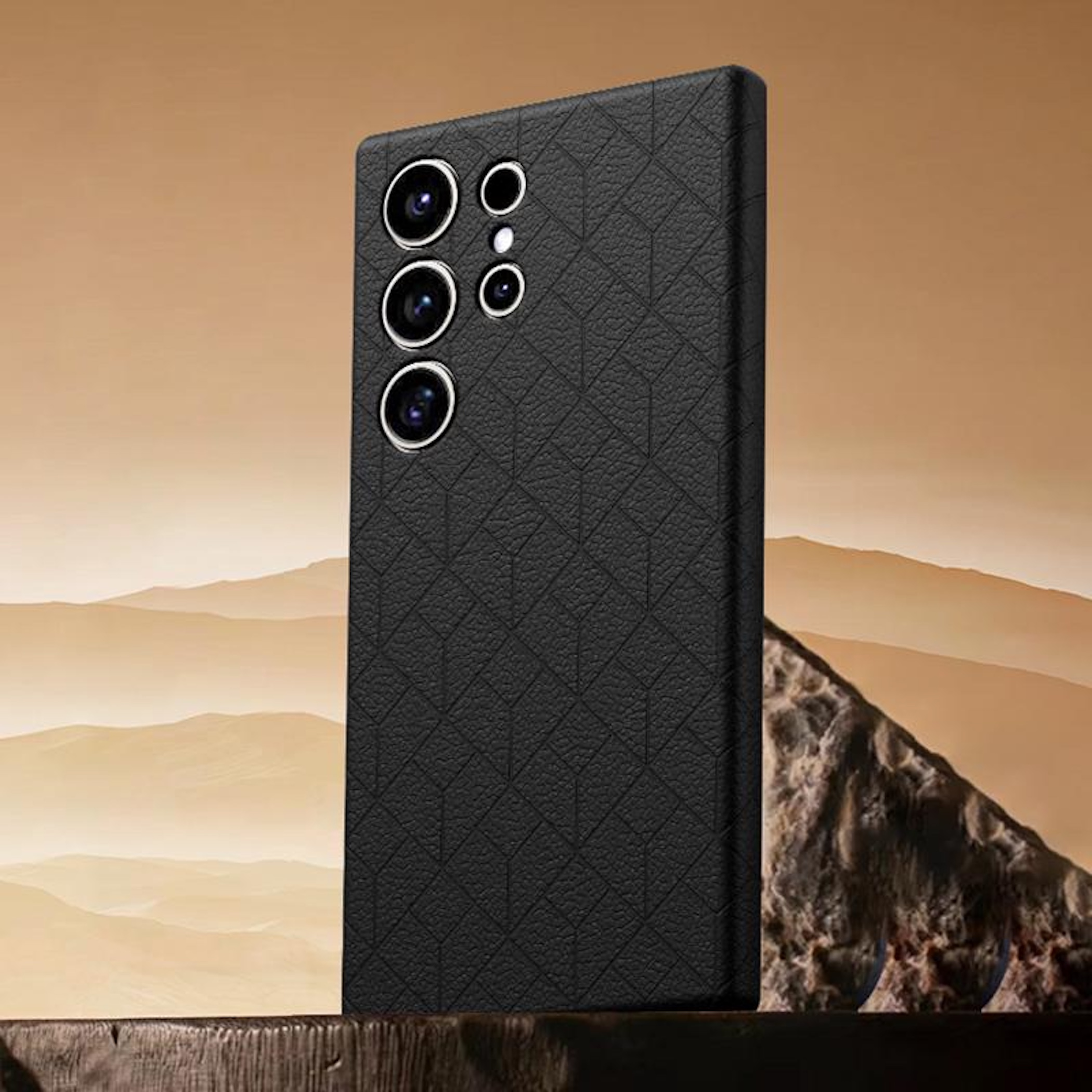 Schwarzes Handy-Cover mit geometrischem Muster vor Berglandschaft.