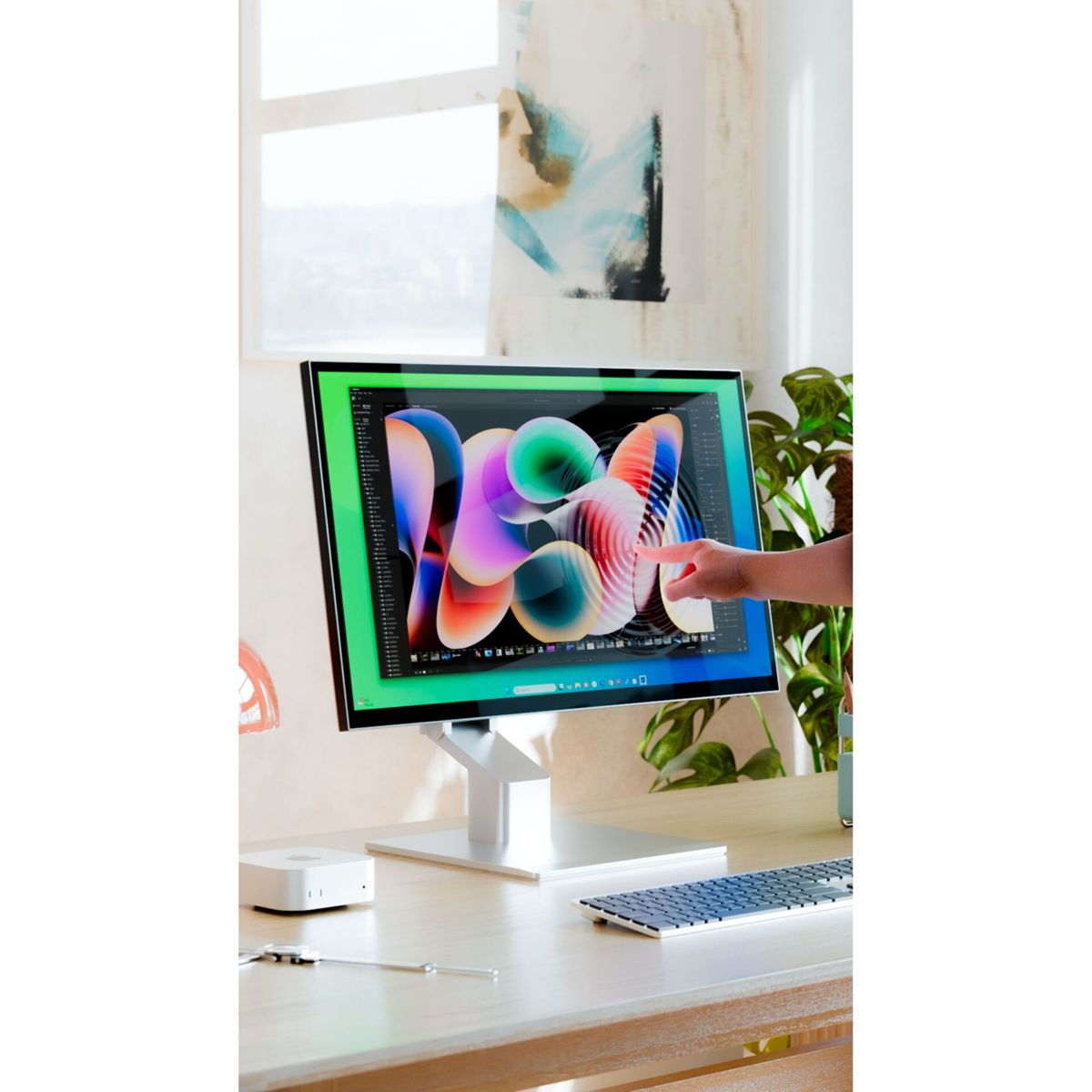 La mano di una persona indica un disegno astratto colorato su uno schermo del computer.