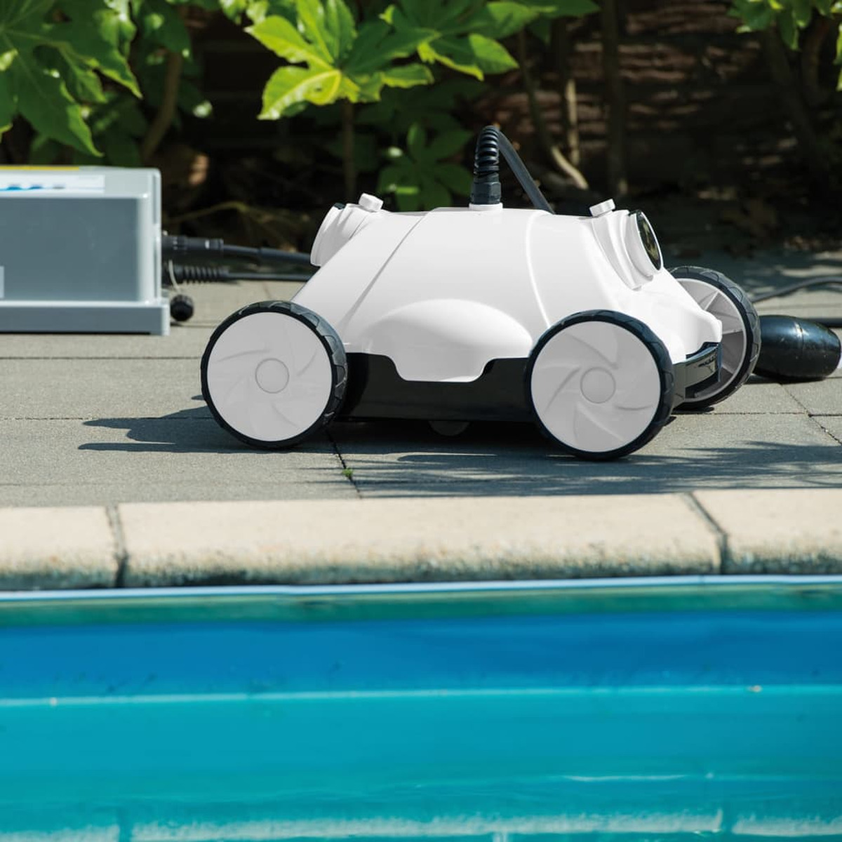 Ein weißer Poolroboter mit schwarzen Rädern steht auf Steinplatten neben einem blauen Pool.
