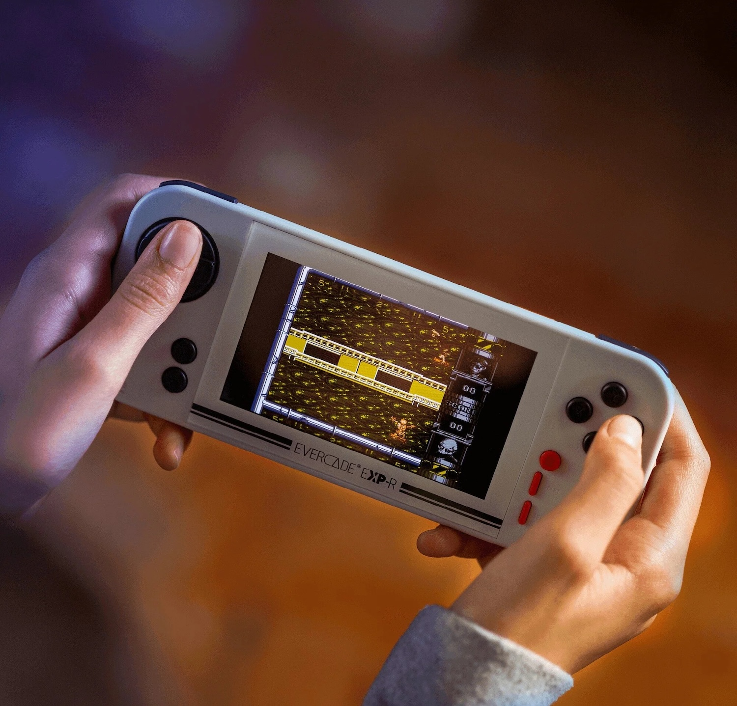 Manos sosteniendo una consola de videojuegos portátil blanca jugando un juego pixelado con elementos amarillos y negros.