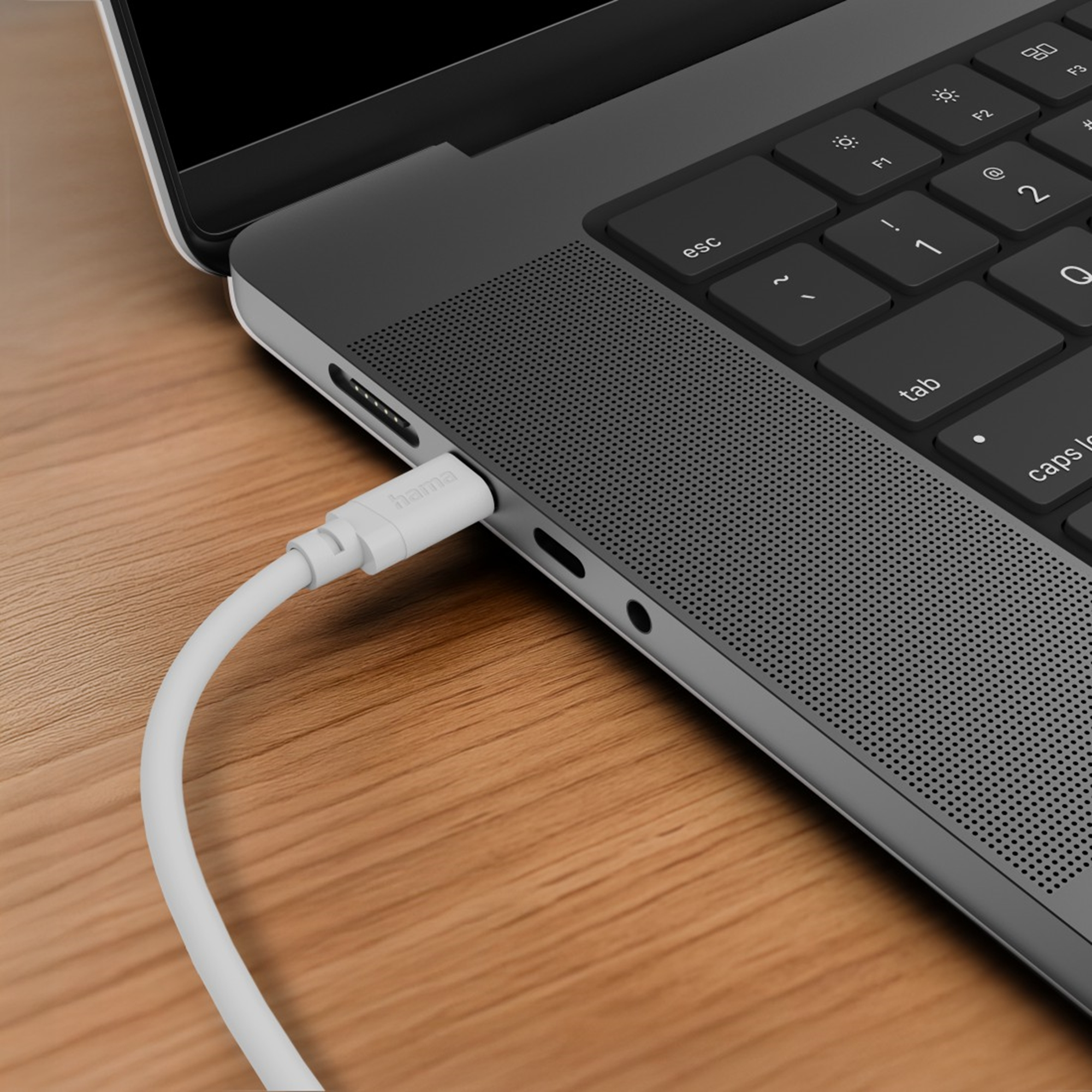 Ein weißes Kabel mit Hama-Logo ist in einen grauen Laptop eingesteckt.