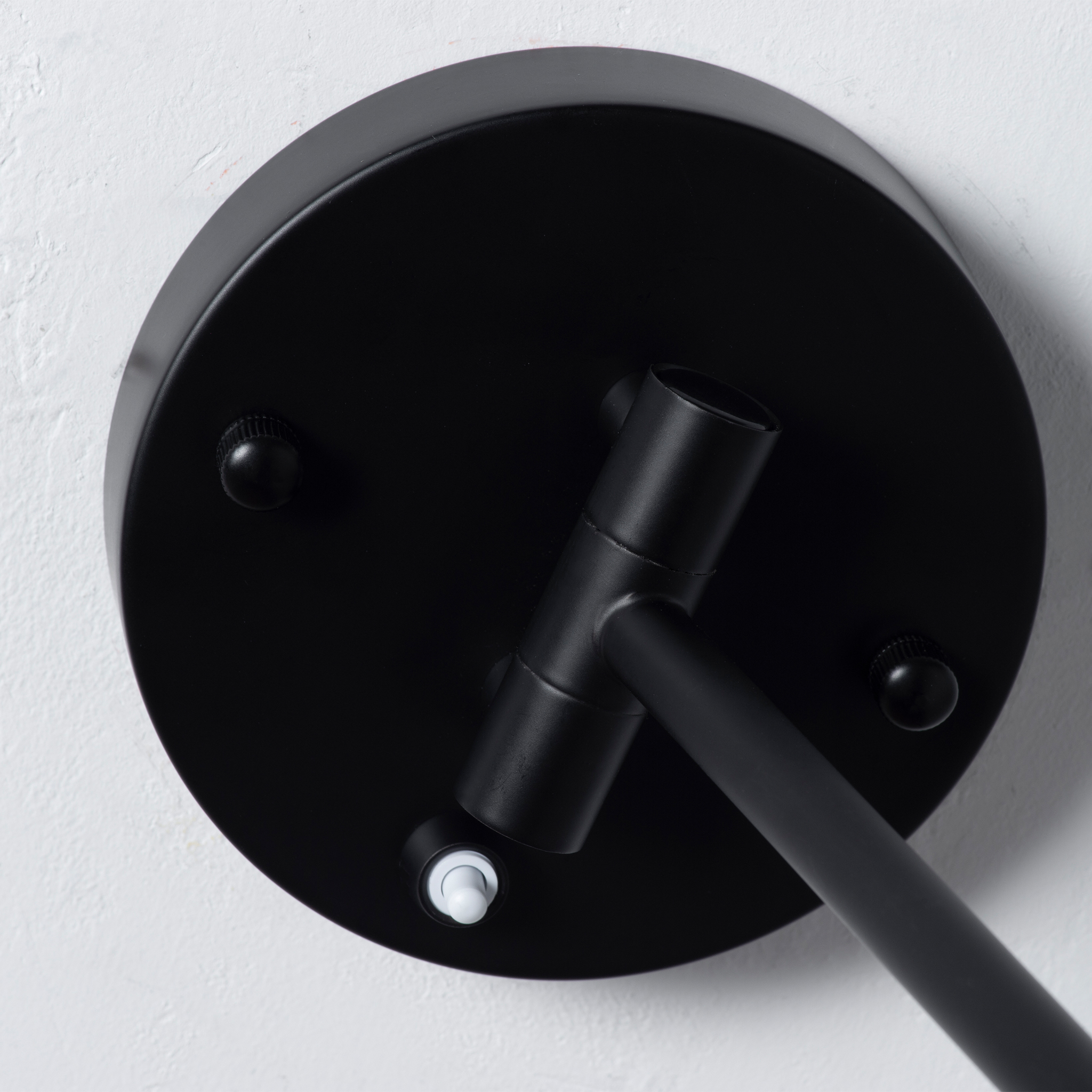 Un primer plano de una lámpara de techo negra con un pequeño interruptor blanco.