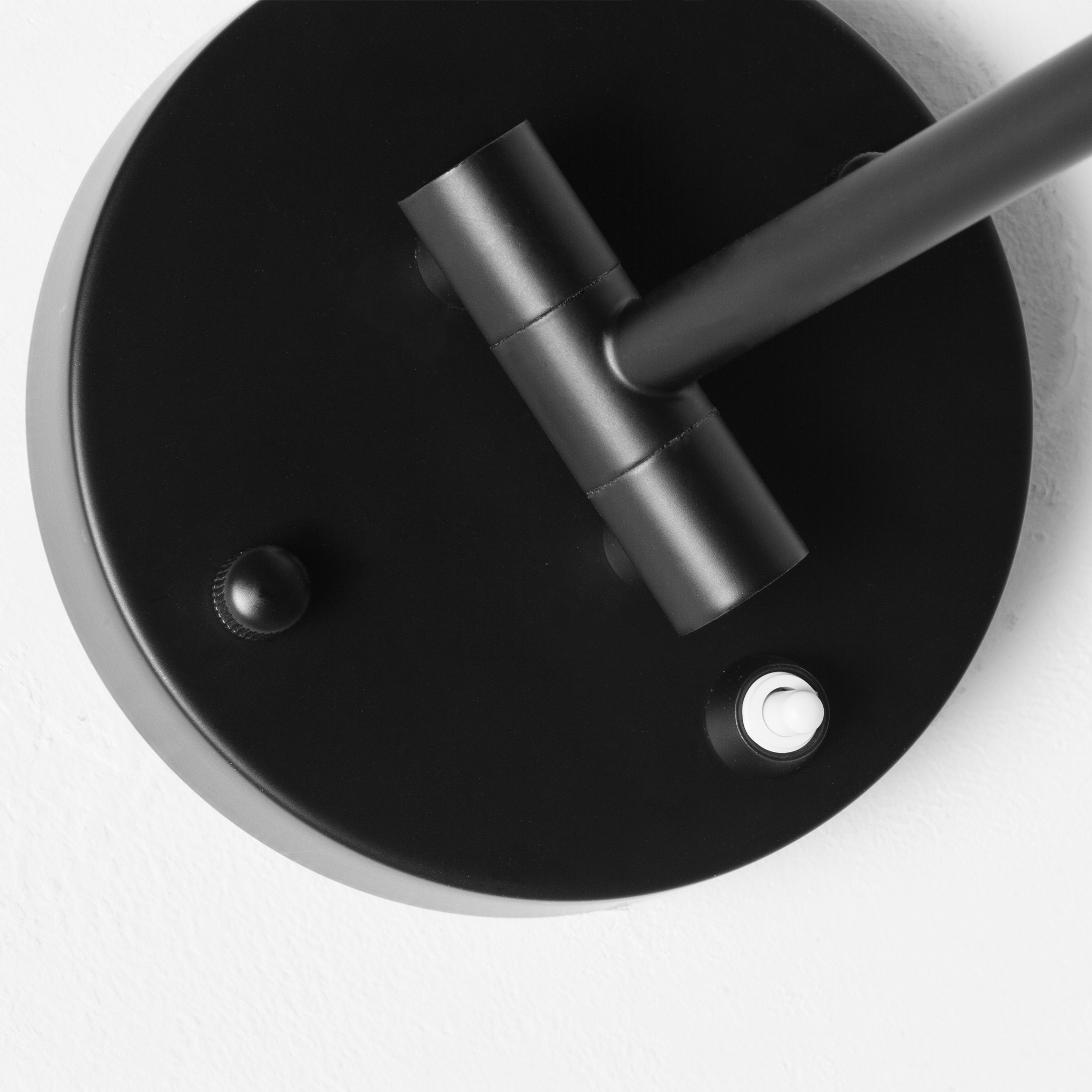 Primer plano de un brazo de lámpara negro con cabeza giratoria y interruptor.