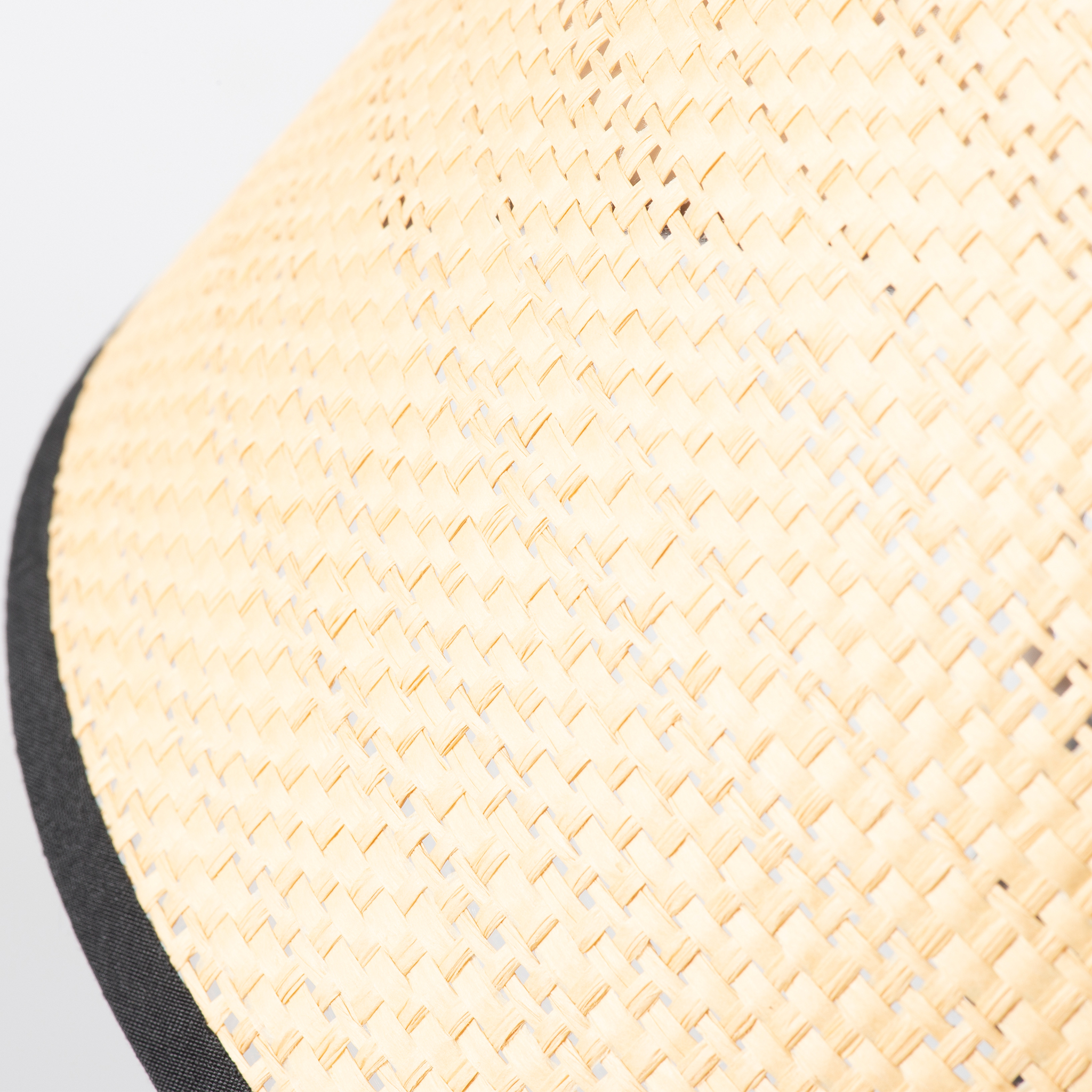 Primer plano de un sombrero tejido con ala negra sobre fondo blanco.