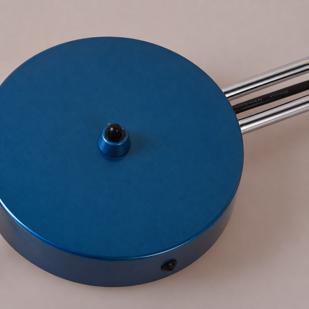 Una base de lámpara redonda azul con un pomo negro y brazos metálicos.