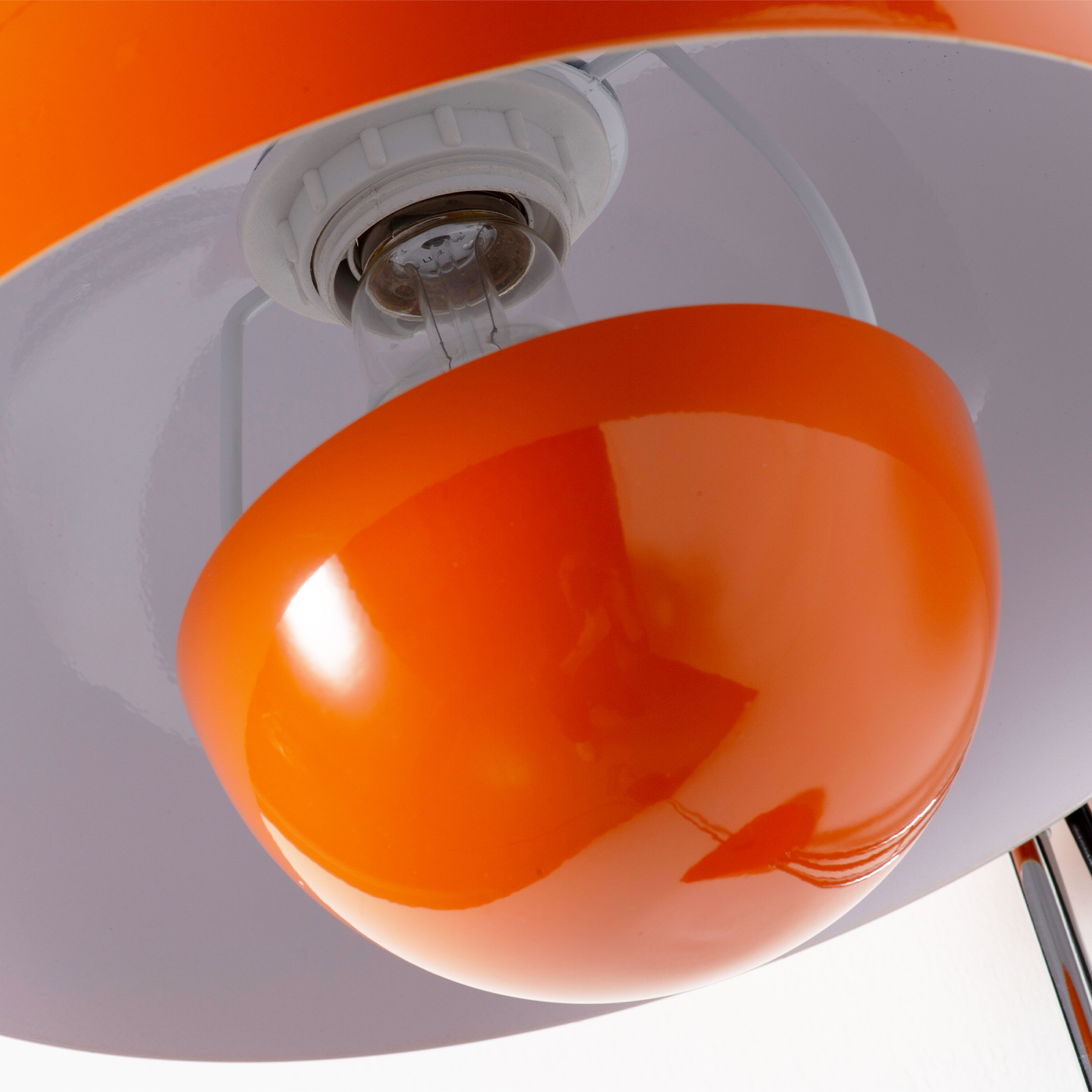 Primer plano de una lámpara naranja con bombilla y portalámparas blanco.