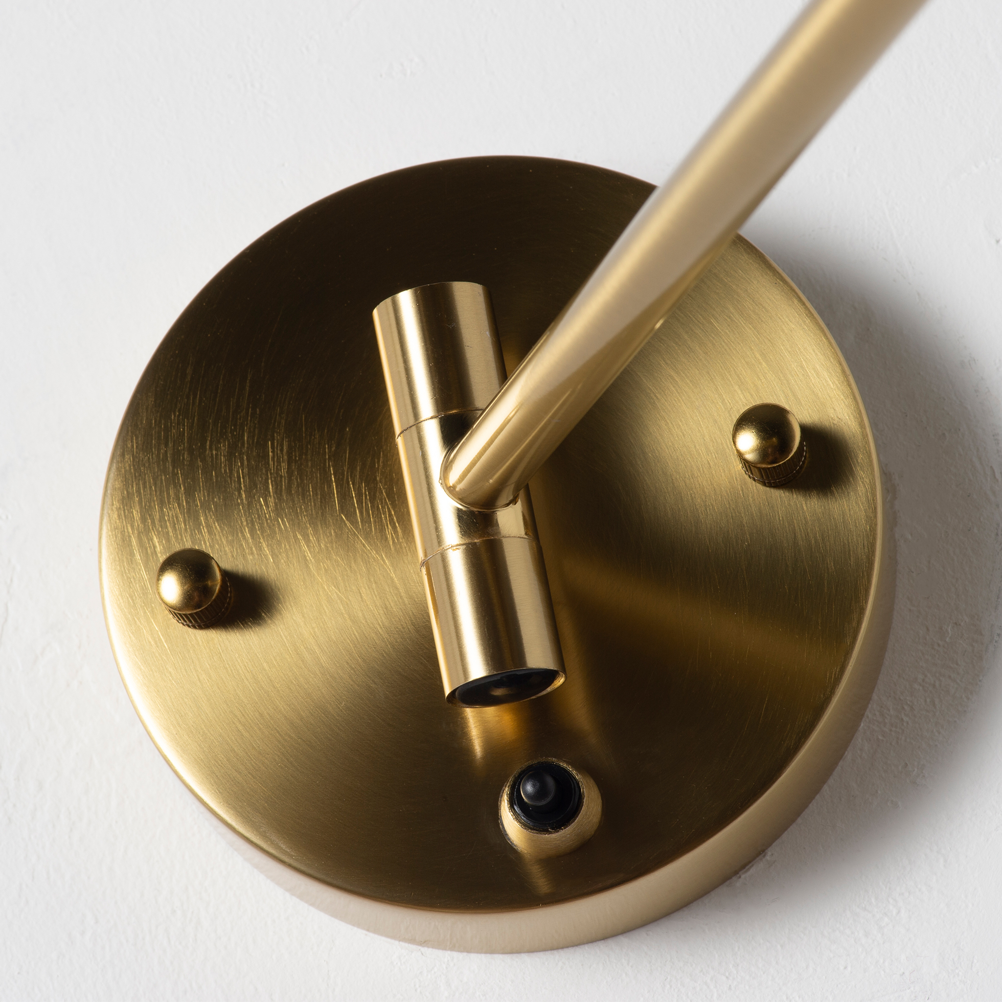 Aplique de pared de latón con brazo ajustable e interruptor.