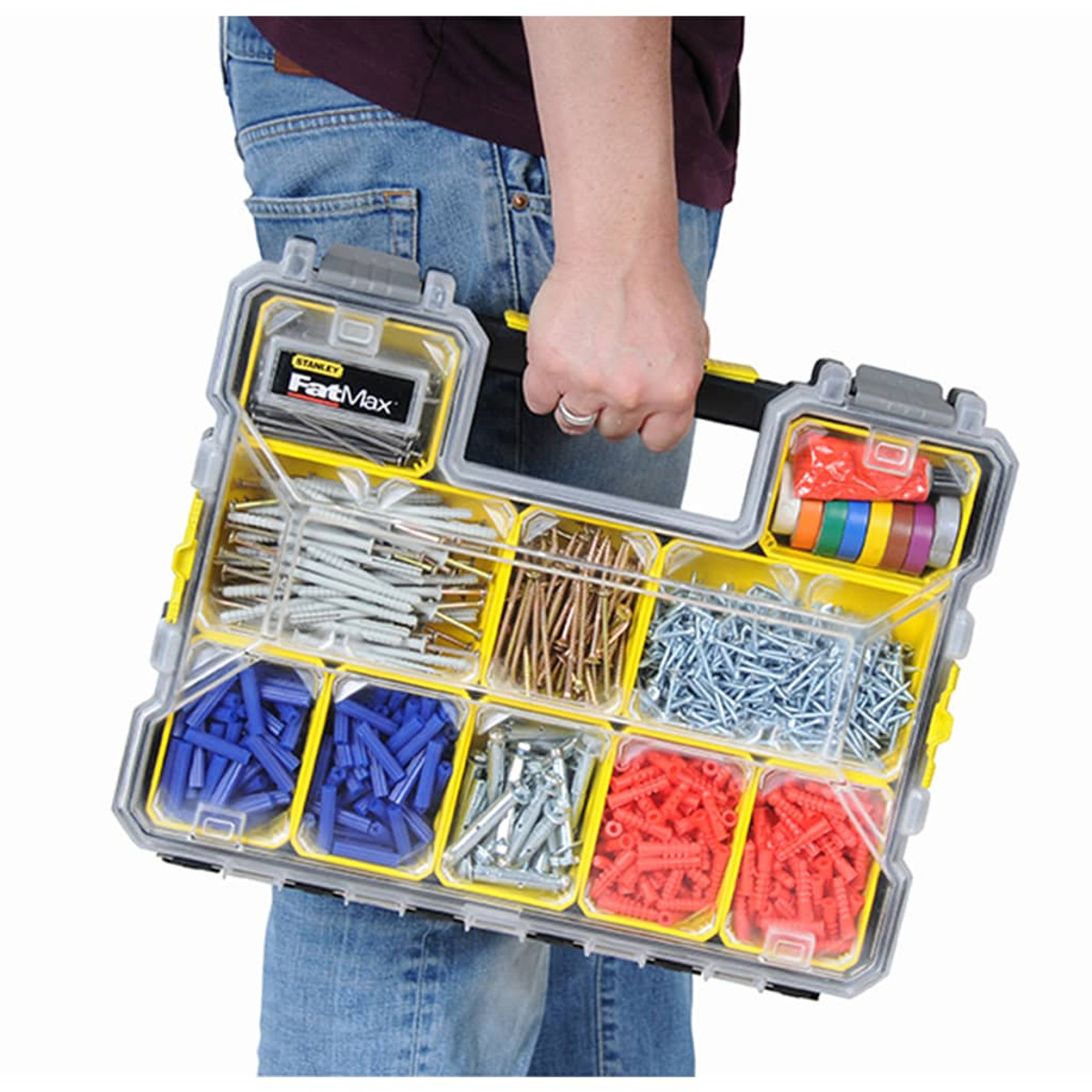 Una persona in jeans tiene una cassetta degli attrezzi con viti, tasselli e ferramenta.