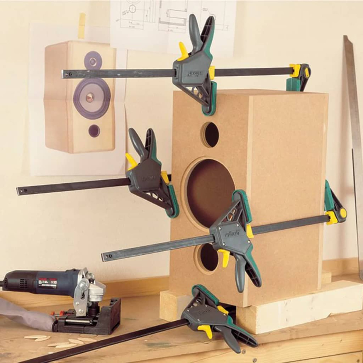 Holzgehäuse mit vier Zwingen, Schleifmaschine und Bauplan.