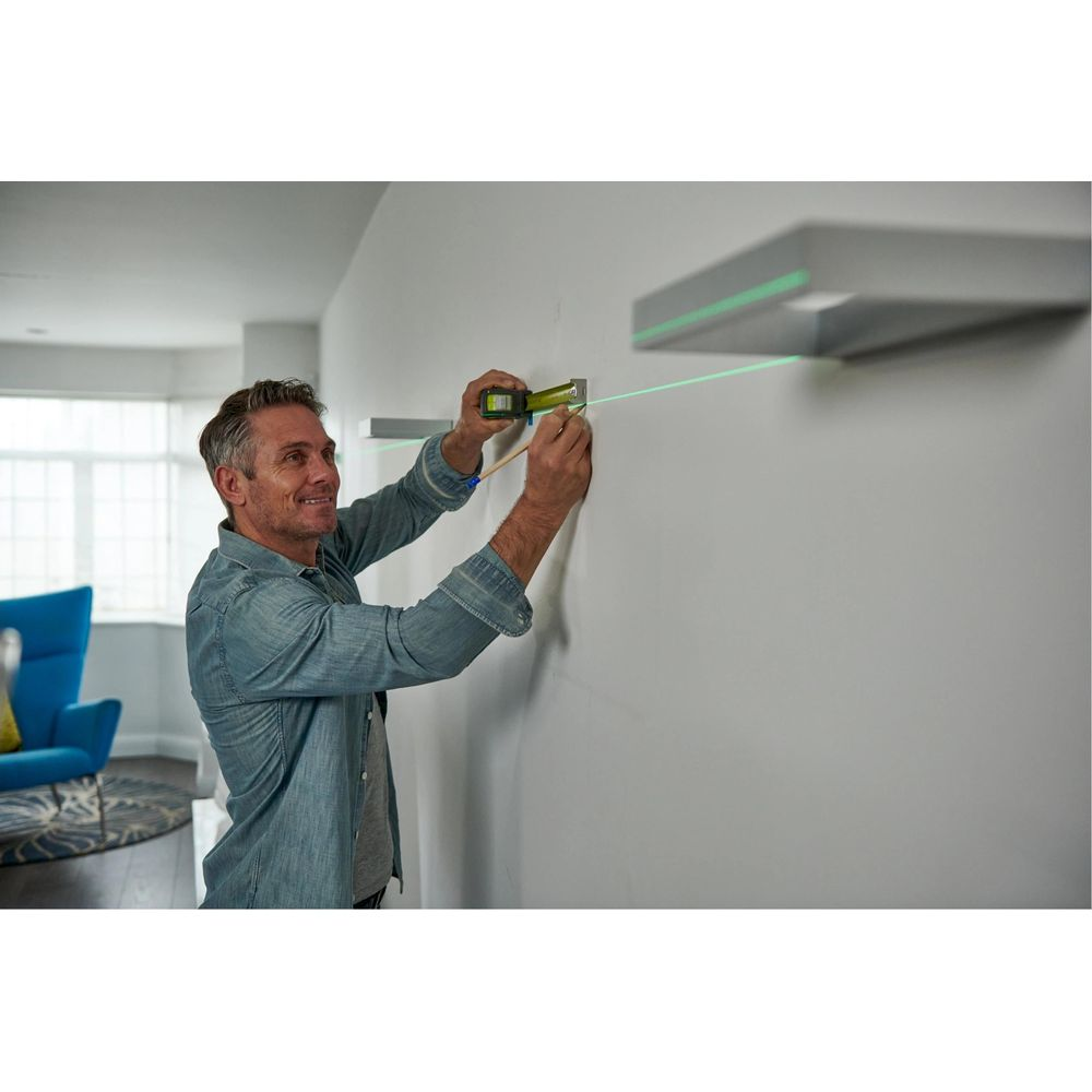 Ein Mann benutzt einen Laser-Wasserwaage und Maßband, um eine Linie an einer Wand zu markieren.