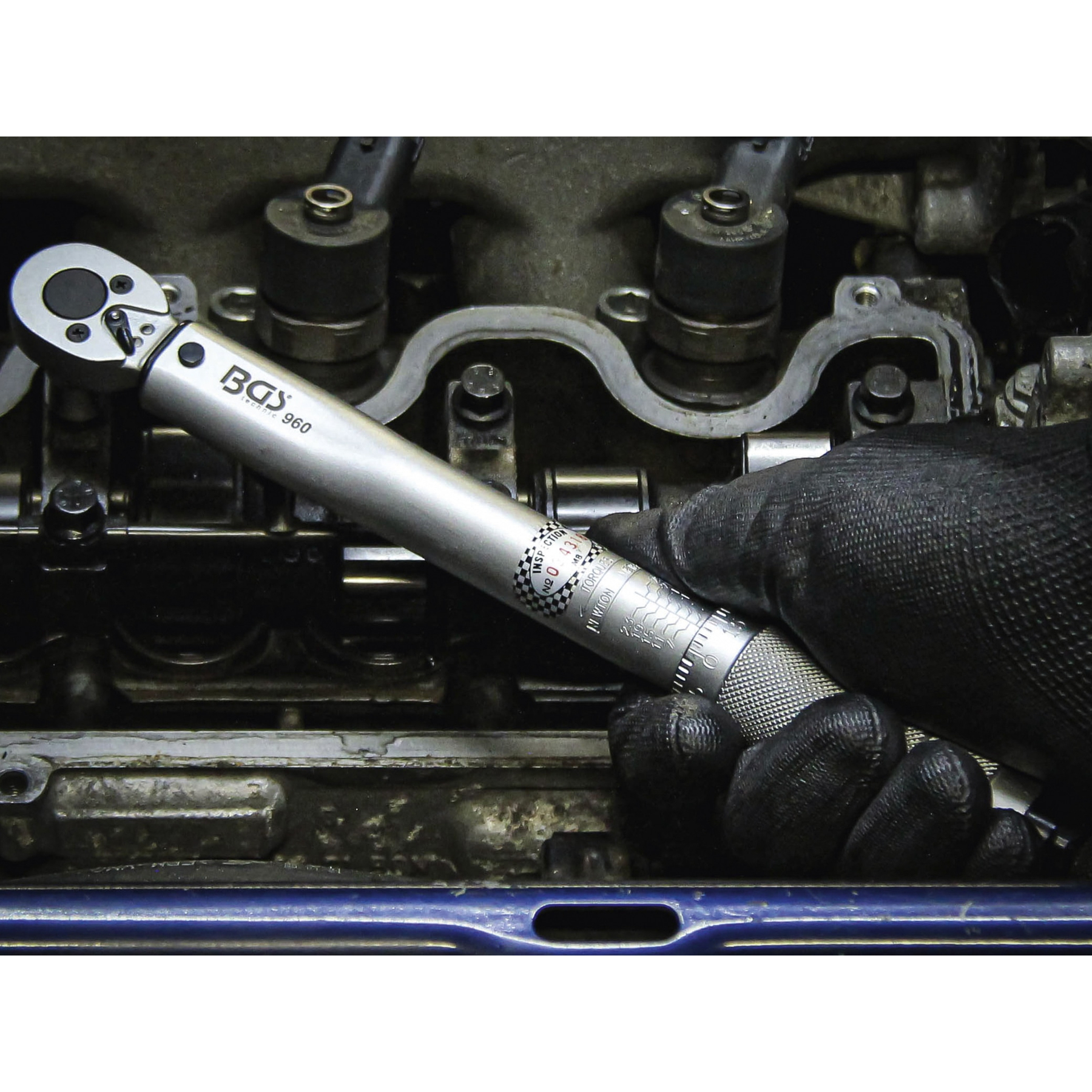 Eine Hand mit schwarzer Handschuh benutzt einen Drehmomentschlüssel im Motor.