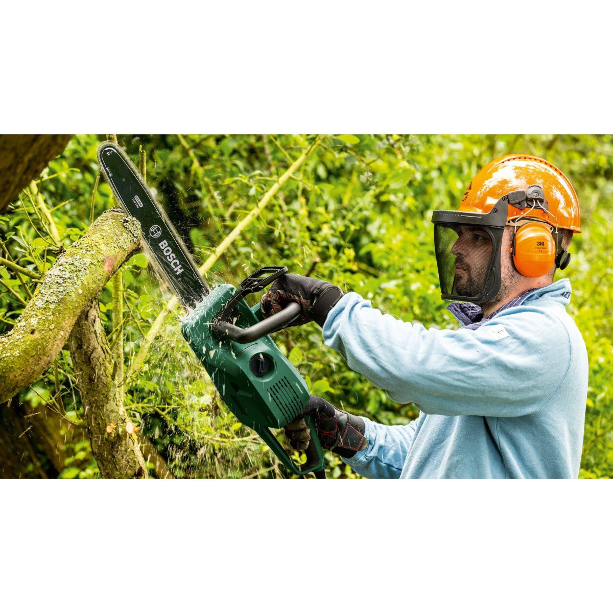 Mann mit orangefarbenem Helm und Gehörschutz schneidet Ast mit Kettensäge.