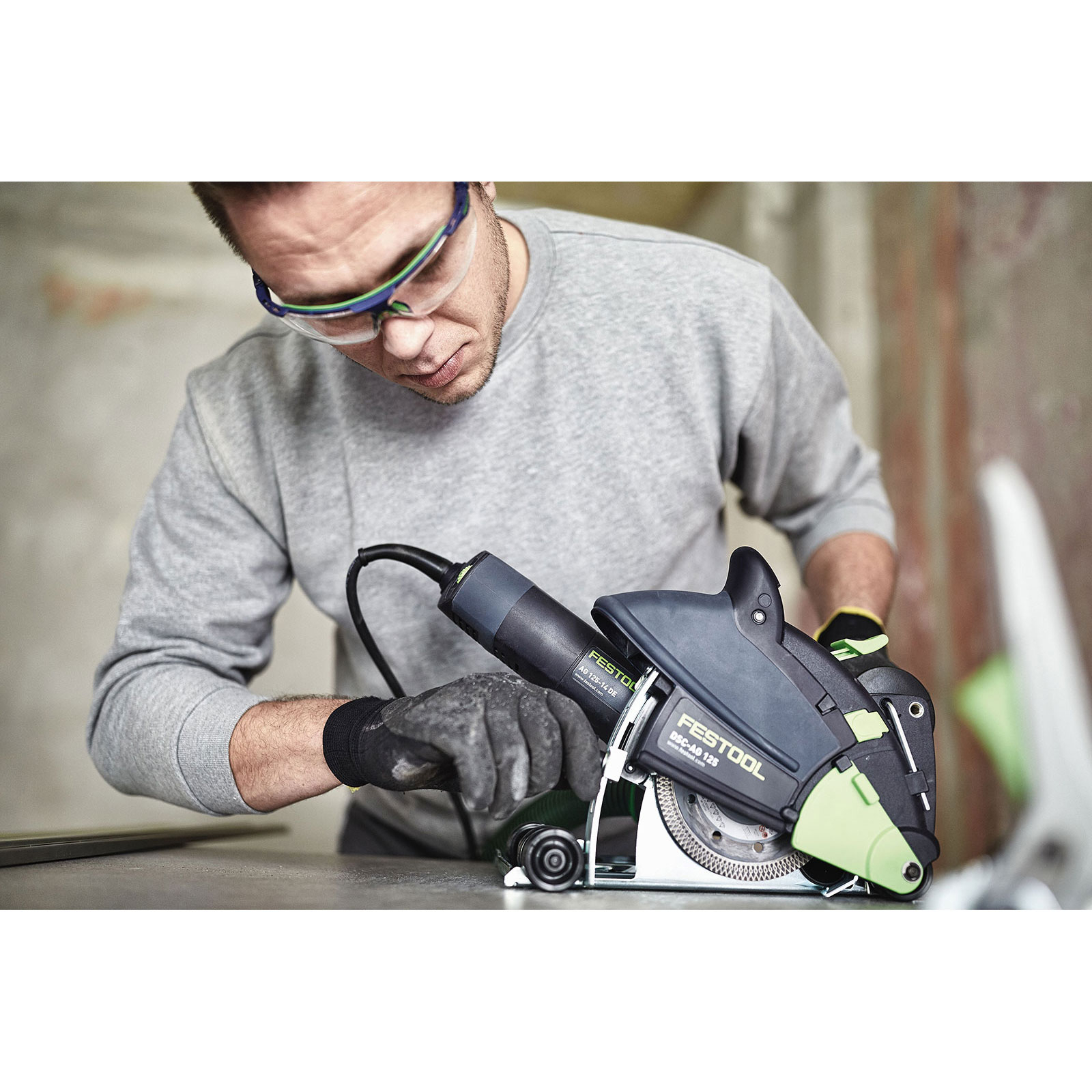 Mann mit Schutzbrille und Handschuhen bedient Festool Trennschleifer.
