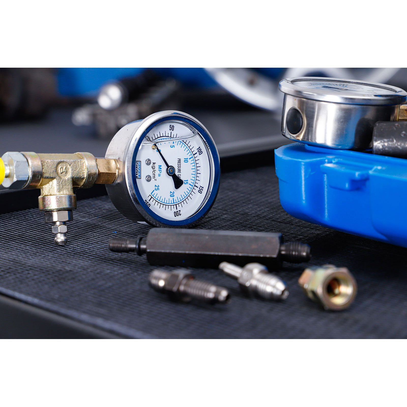 Ein Manometer mit Messingfitting und gelber Kappe liegt auf texturierter Oberfläche.