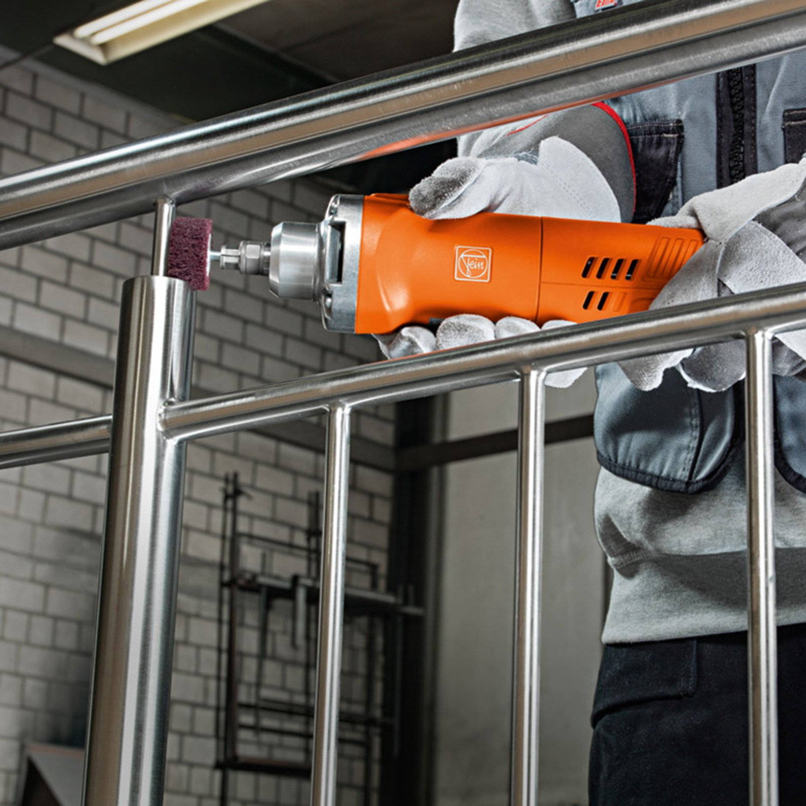 Mann mit orangefarbenem Schleifgerät bearbeitet Metallgeländer.