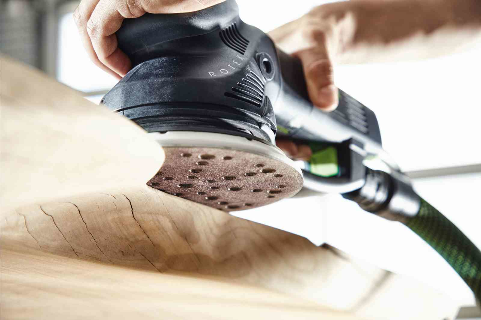Ein Handwerker schleift Holz mit einem Exzenterschleifer.