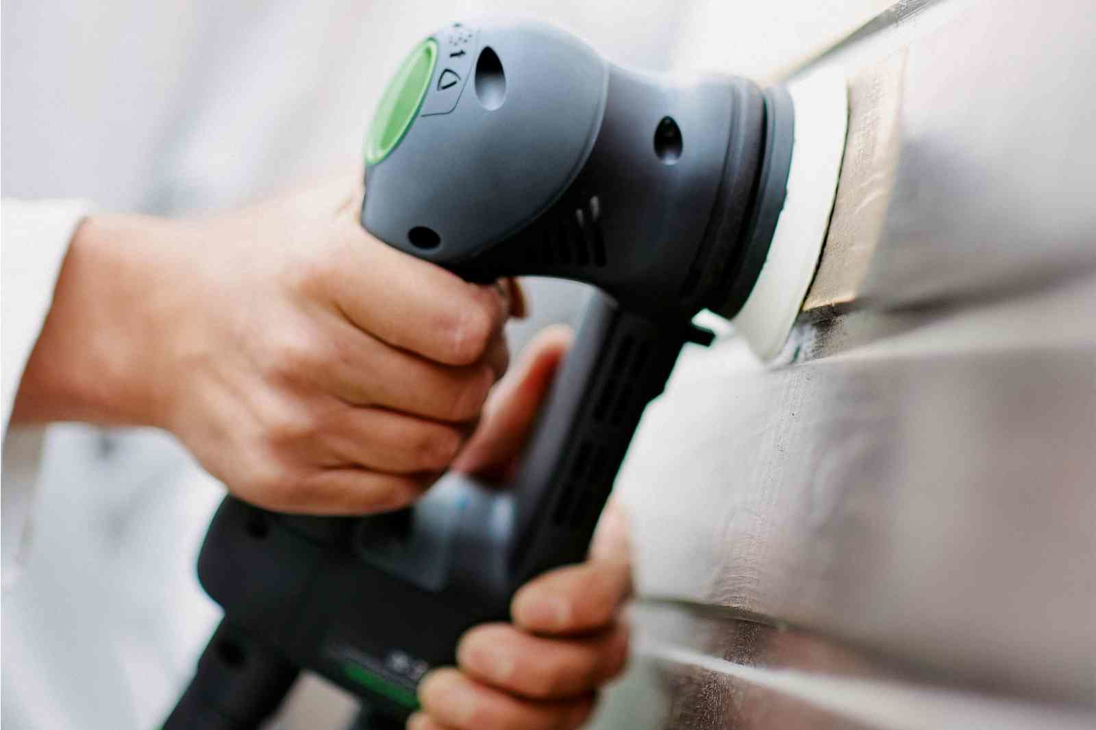 Eine Person poliert eine Oberfläche mit einer elektrischen Poliermaschine.