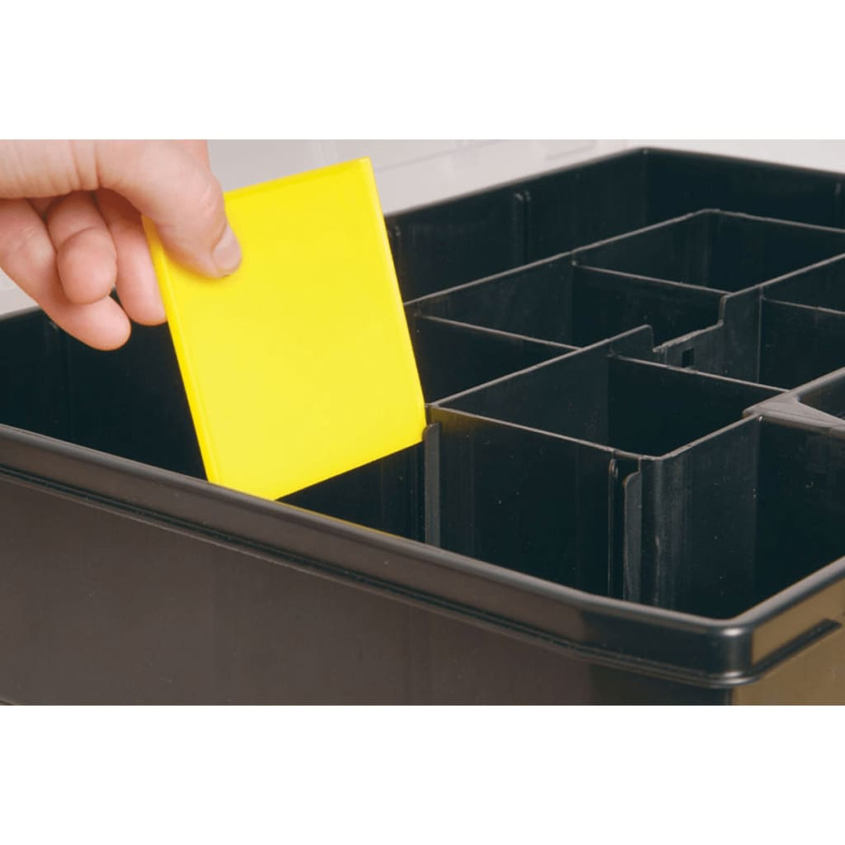 Una mano posiziona un cartellino giallo in un contenitore nero con scomparti.