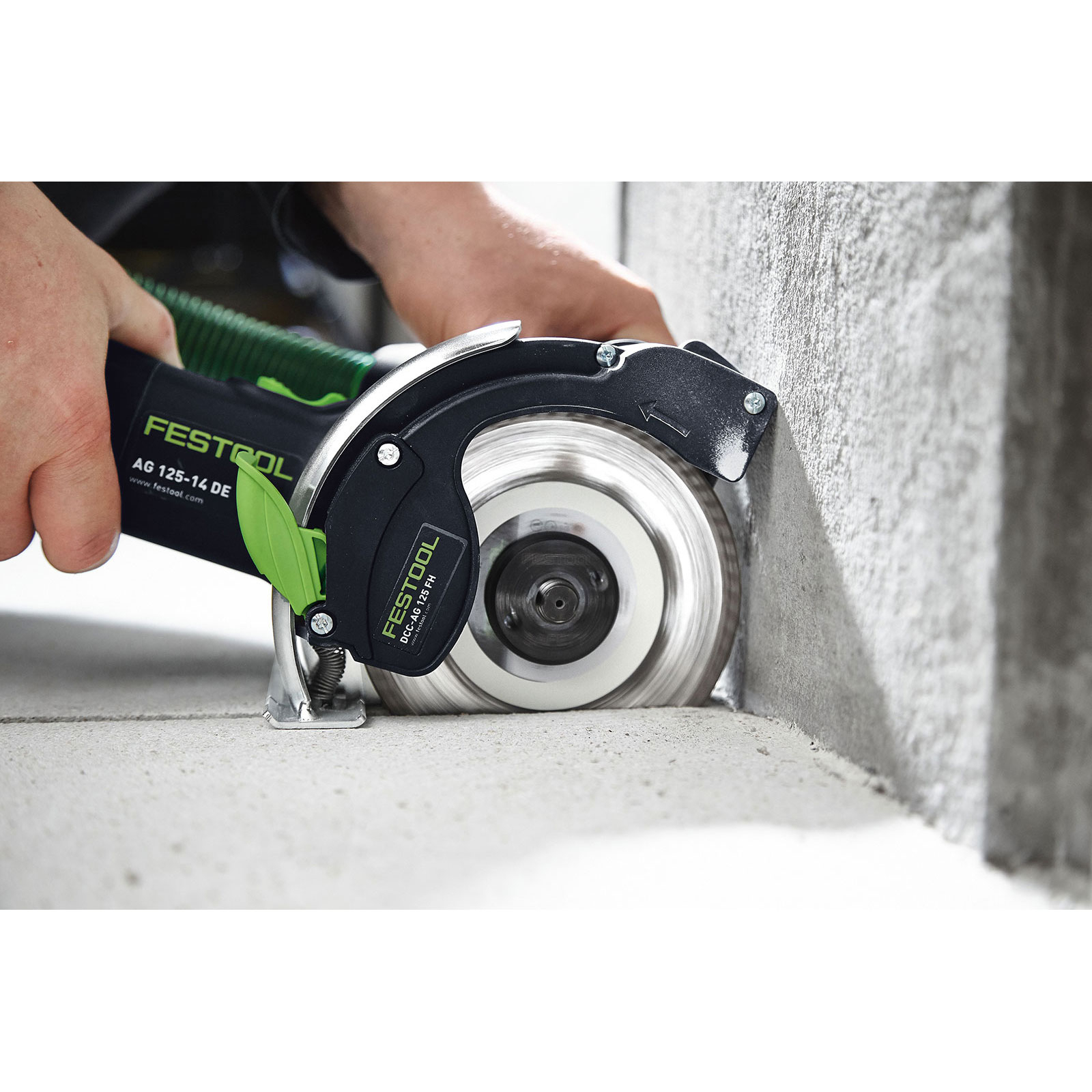 Ein Mann benutzt eine grüne und schwarze Festool-Maschine, um Beton zu schneiden.