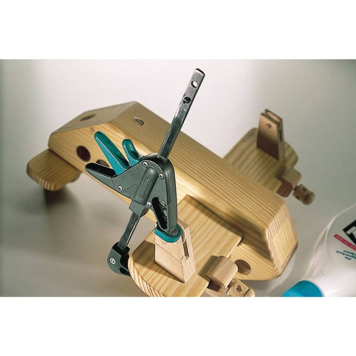 Eine Klemme sichert ein Holzflugzeugmodell im Bau, eine Kleberflasche in der Nähe.