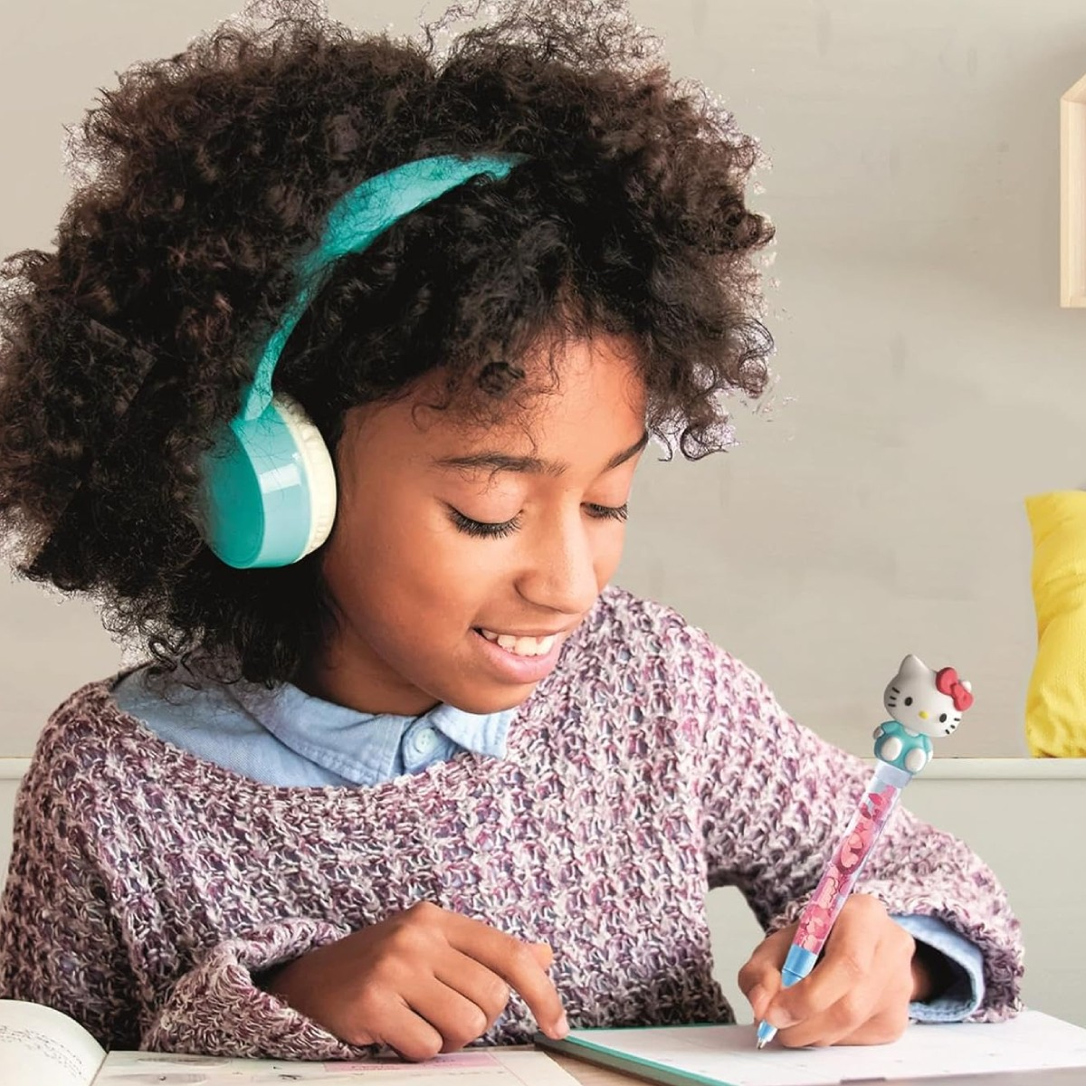 Una ragazza con le cuffie scrive con una penna di Hello Kitty.