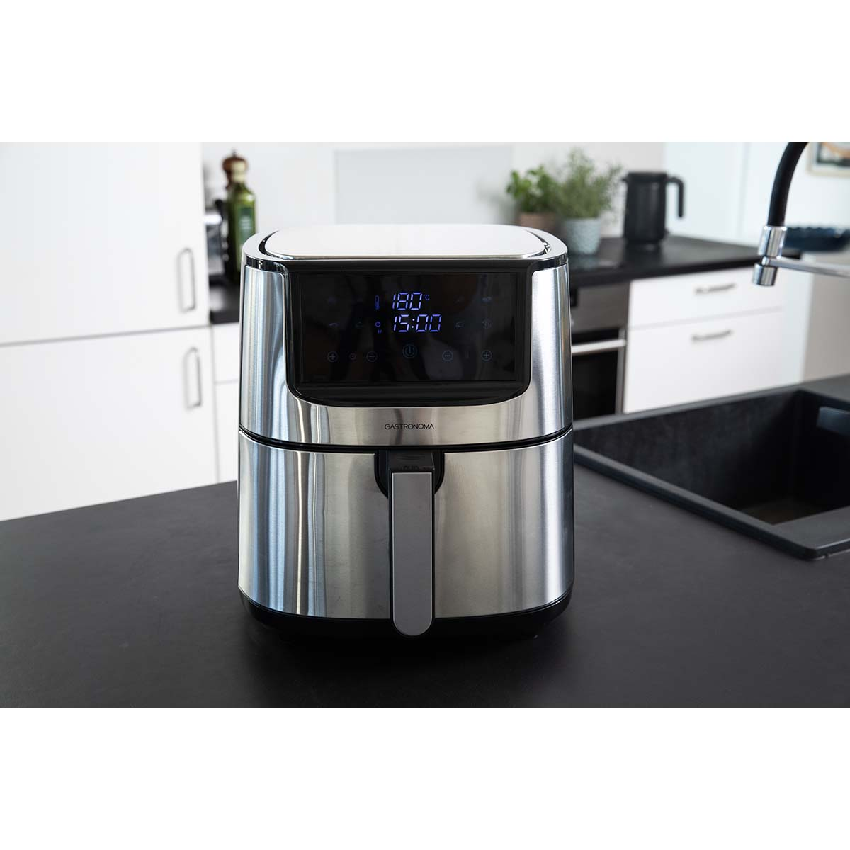 Een zilveren airfryer met digitaal display staat op een donker aanrecht.