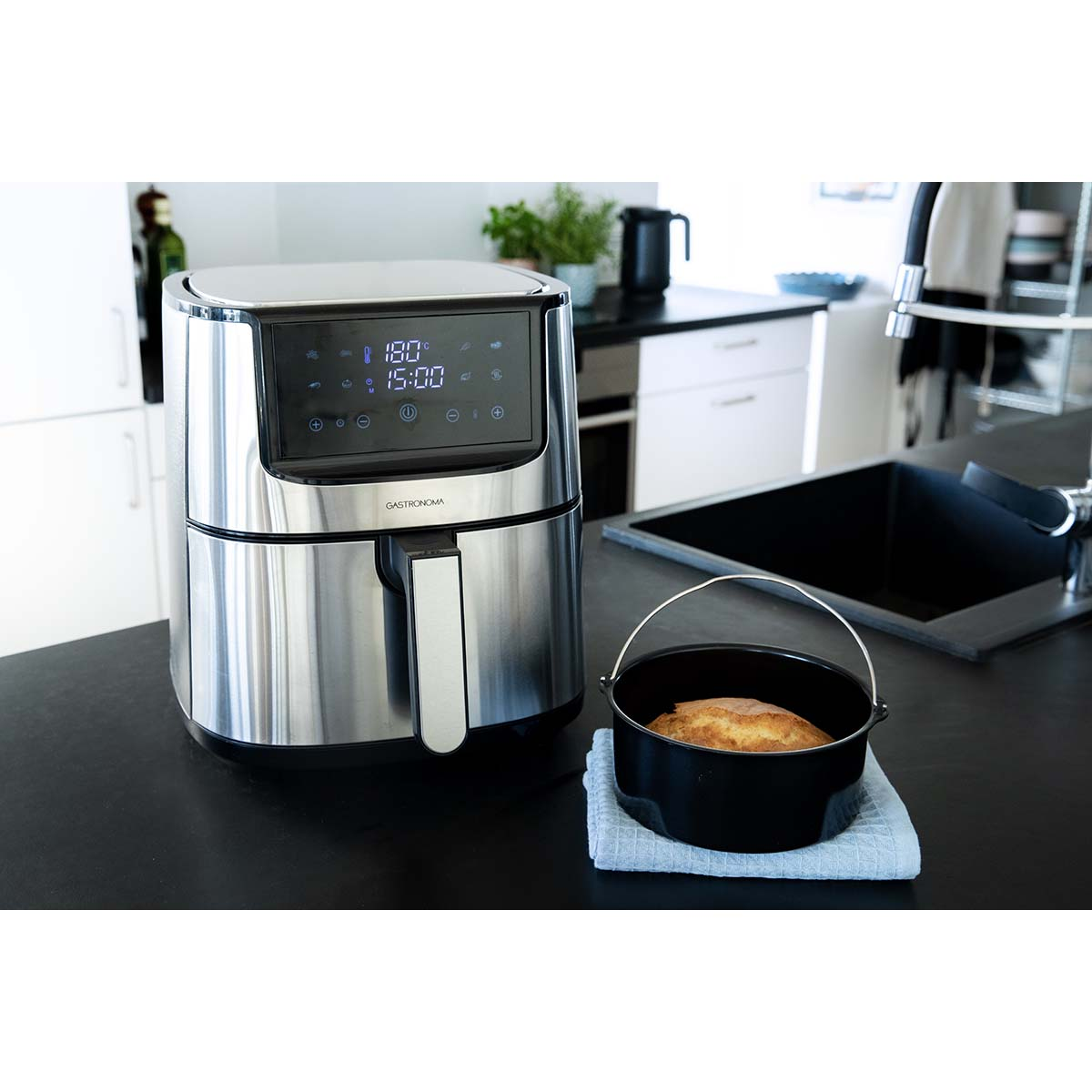 Een zilveren airfryer met digitaal display naast een zwarte pan met brood.