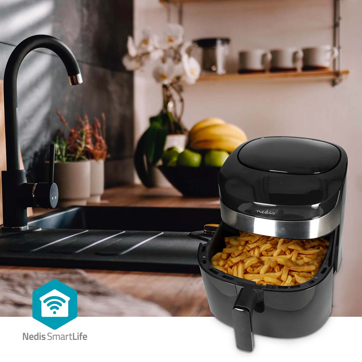 Een zwarte airfryer gevuld met frietjes staat op een aanrecht naast een gootsteen.