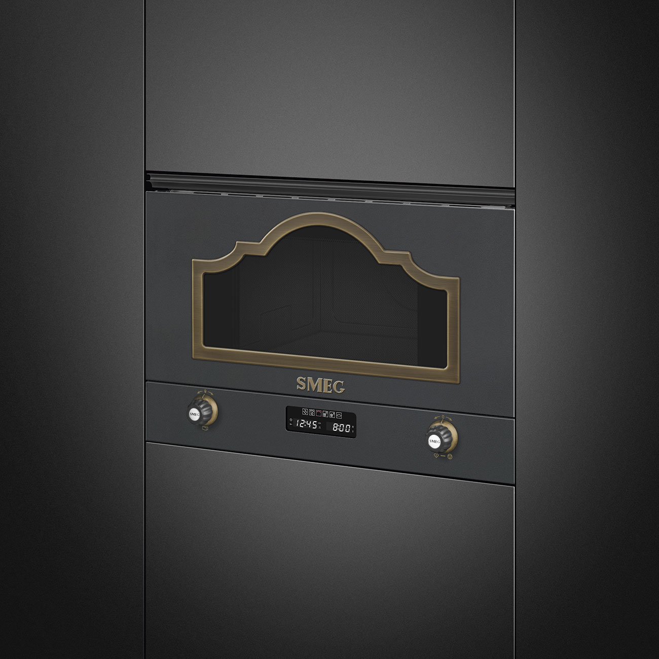 Horno SMEG gris oscuro con borde de latón antiguo alrededor de la ventana y controles digitales.