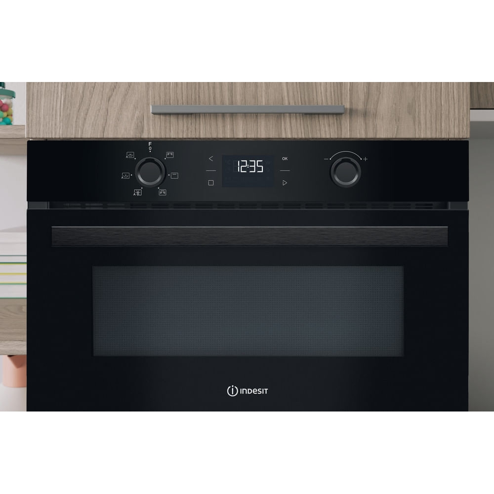 Un microonde Indesit nero con display digitale che mostra le 12:35.
