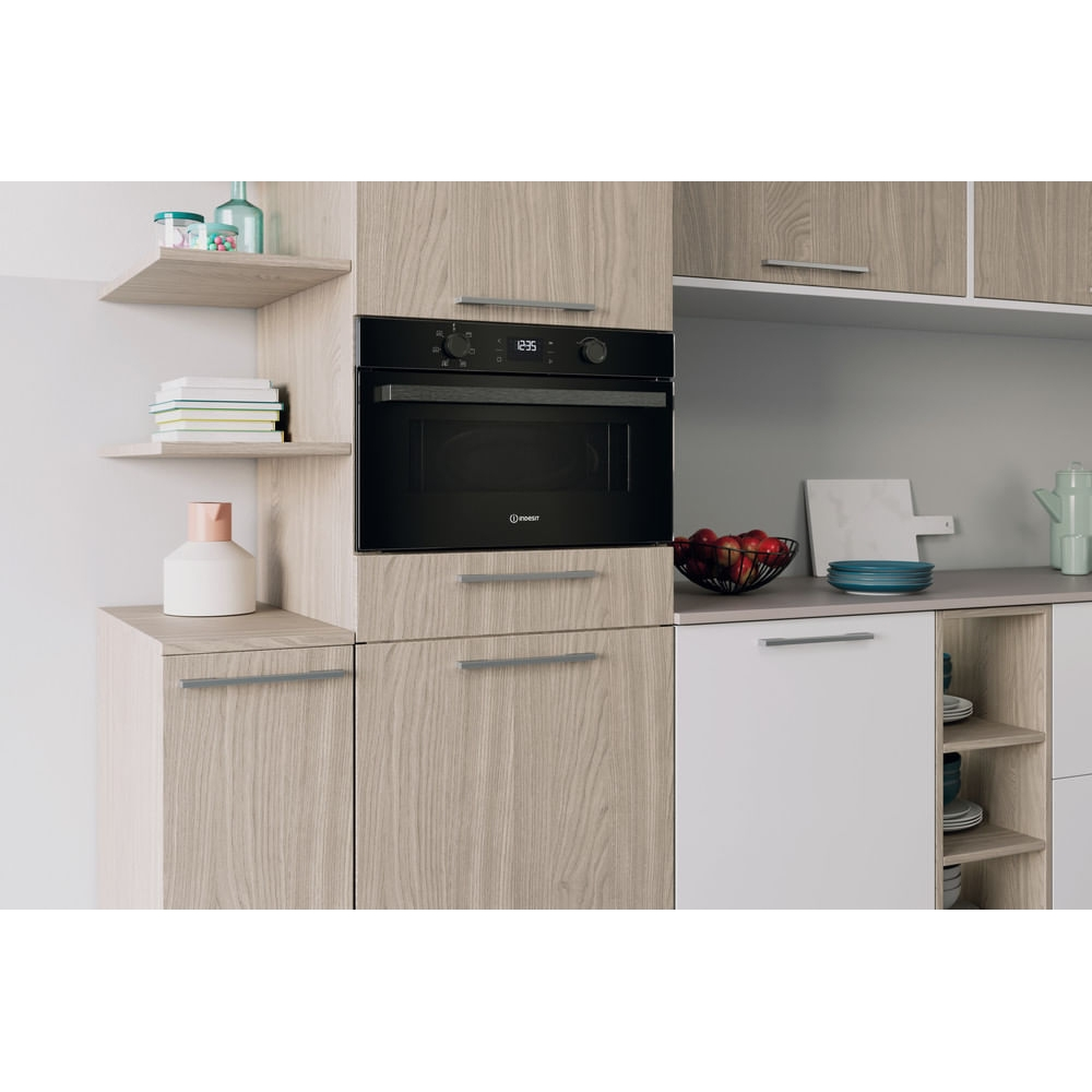 Cucina moderna con forno da incasso, mobili in legno e ciotola di frutta.