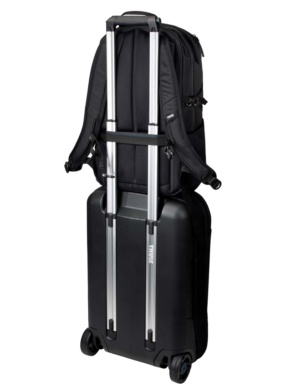 Ein schwarzer Rucksack ist auf einem schwarzen Rollkoffer befestigt.