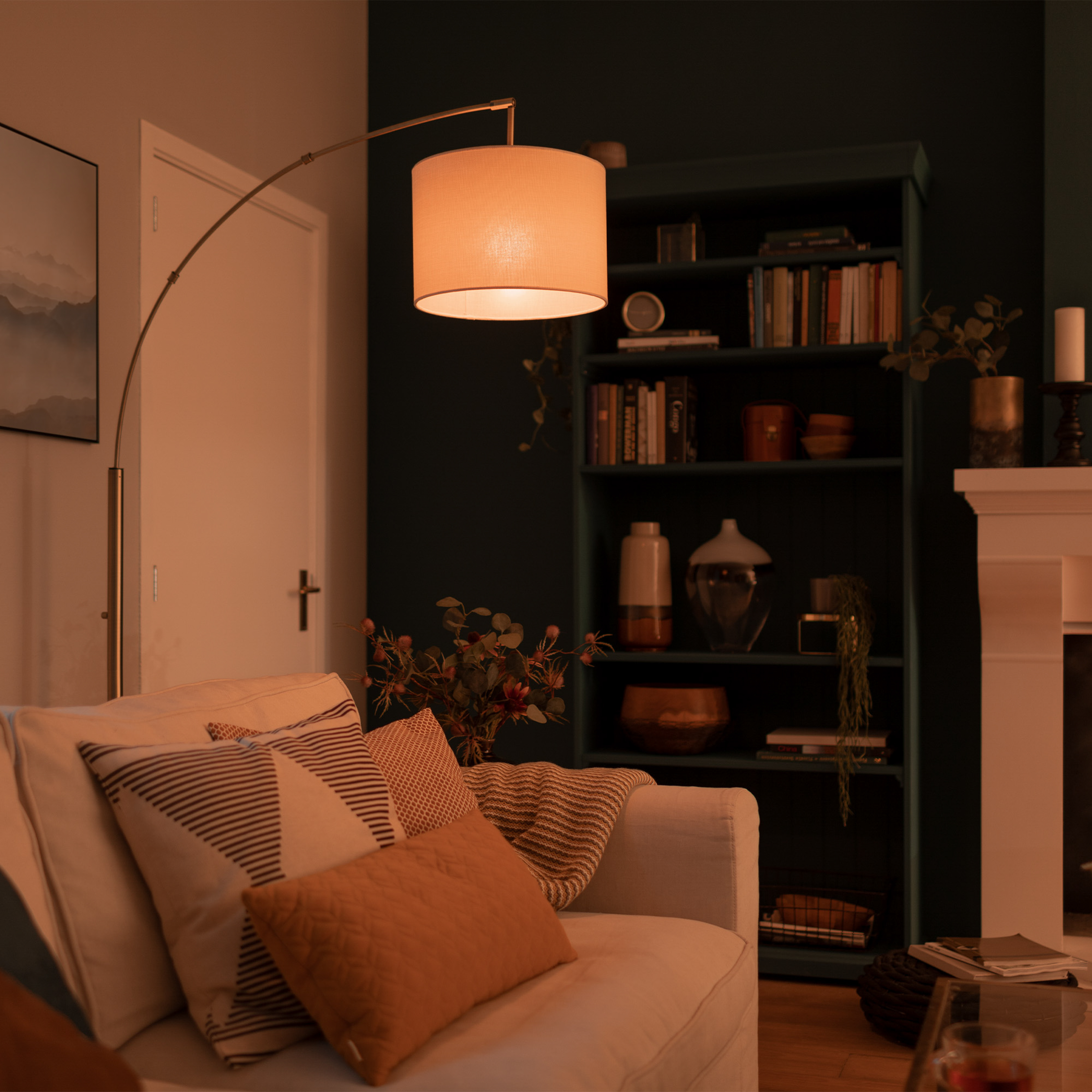 Ein beleuchteter Wohnbereich mit Sofa, Bücherregal und Lampe.